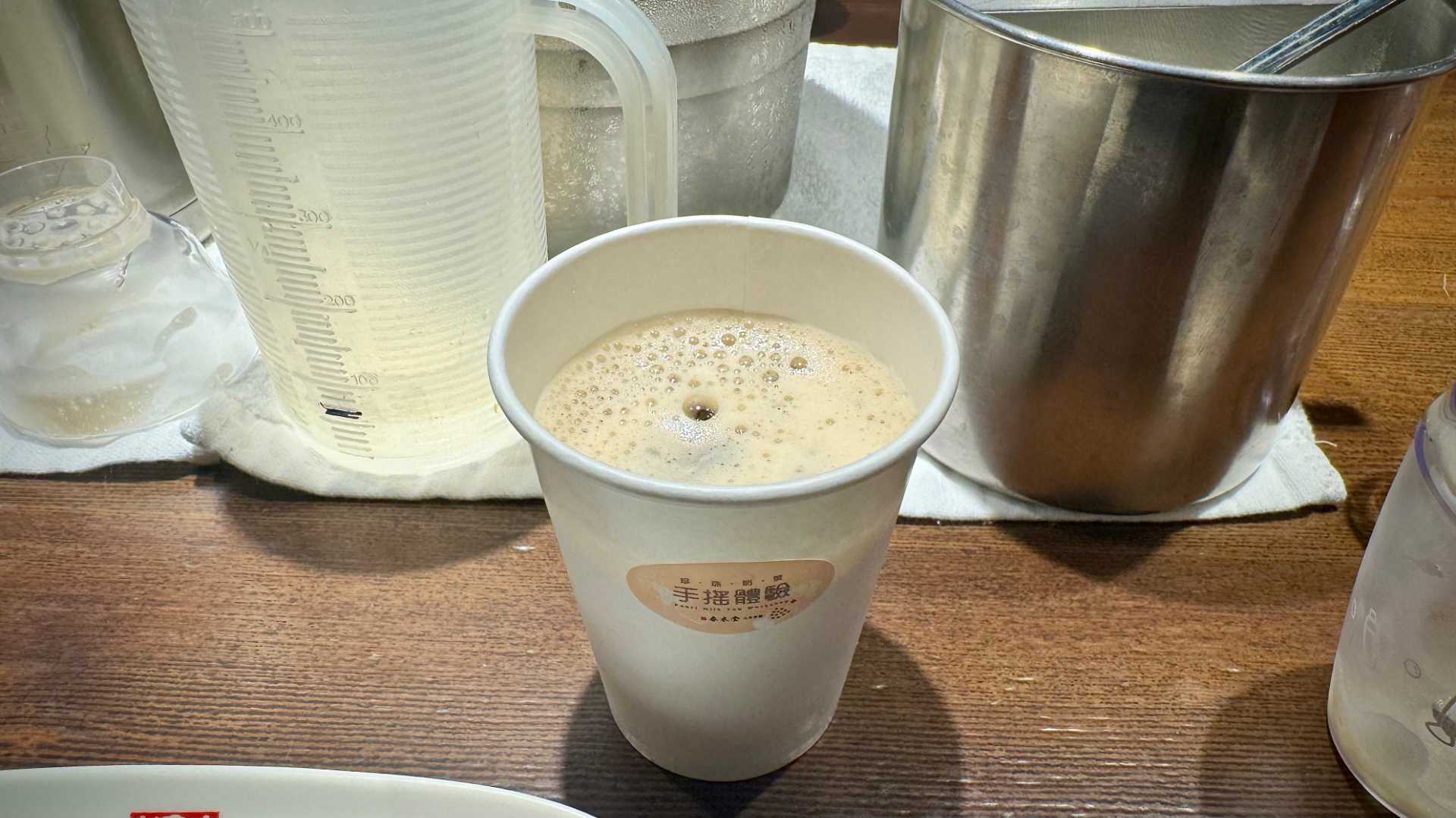 A paper cup filled with frothy black iced tea.