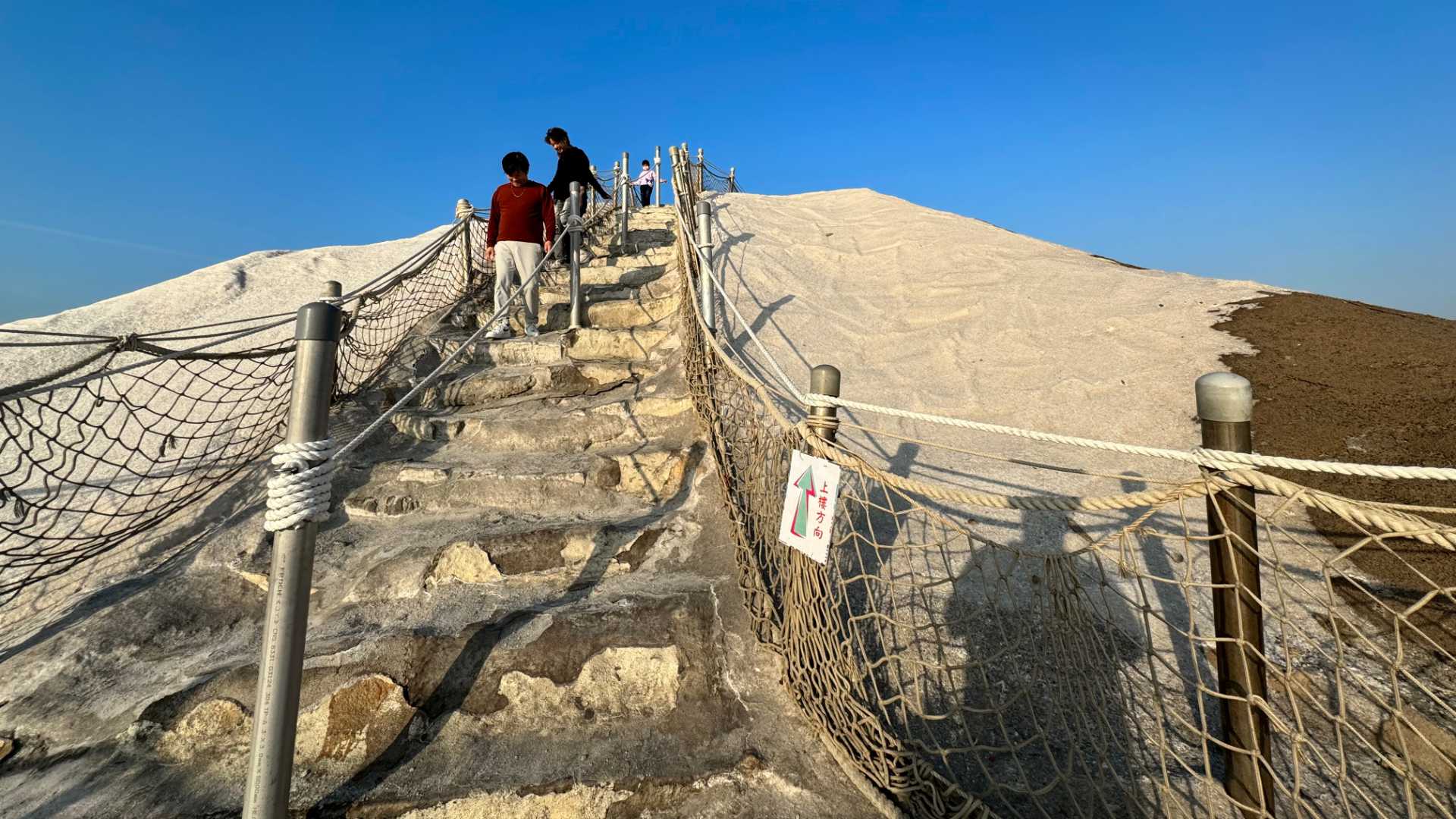 Steps carved into Qigu salt mountain with people carefully descending.