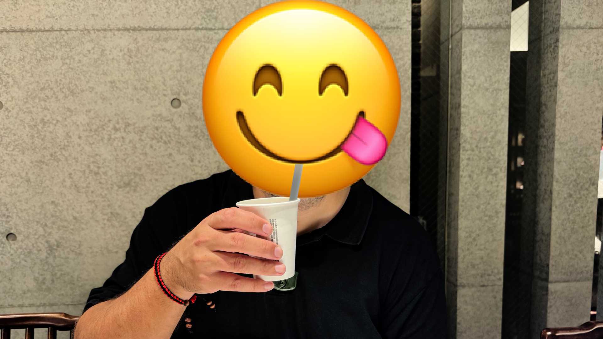 Drinking a freshly-made milk bubble tea through a straw. The person's face is obscured by a licking-their-lips emoji.