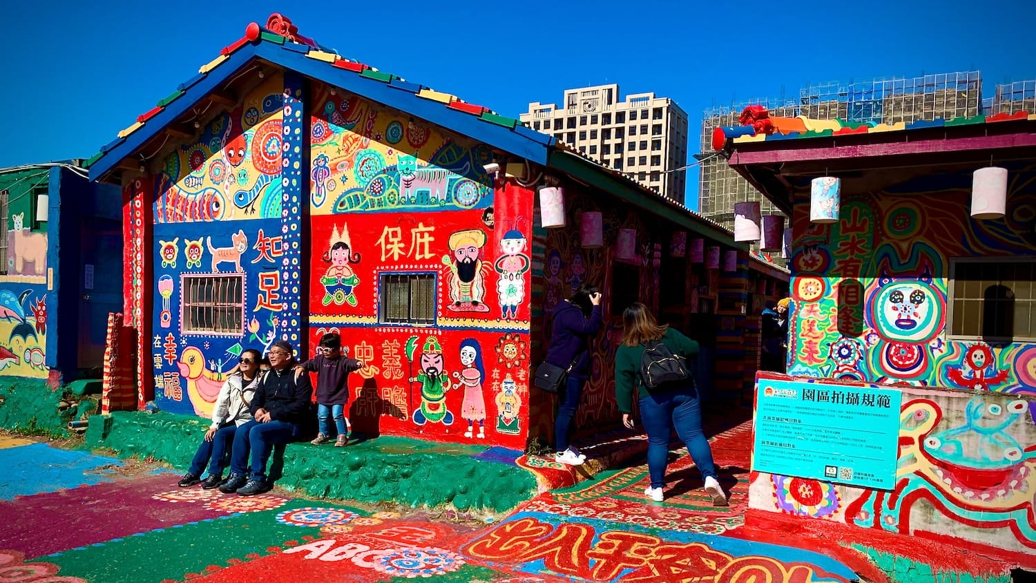 The entrance to Rainbow Village, Taichung, Taiwan, on a bright sunny day. People are posing for photos outside the brightly-painted buildings.