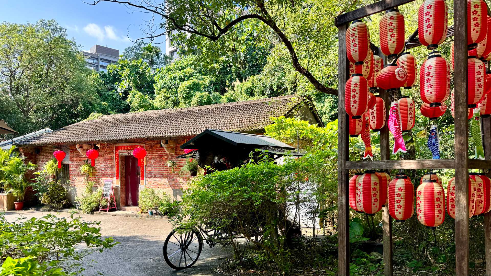 A single-story brick building that appears well-maintained, with lanterns hanging from the front eaves and a traditional-style bicycle parked out the front.