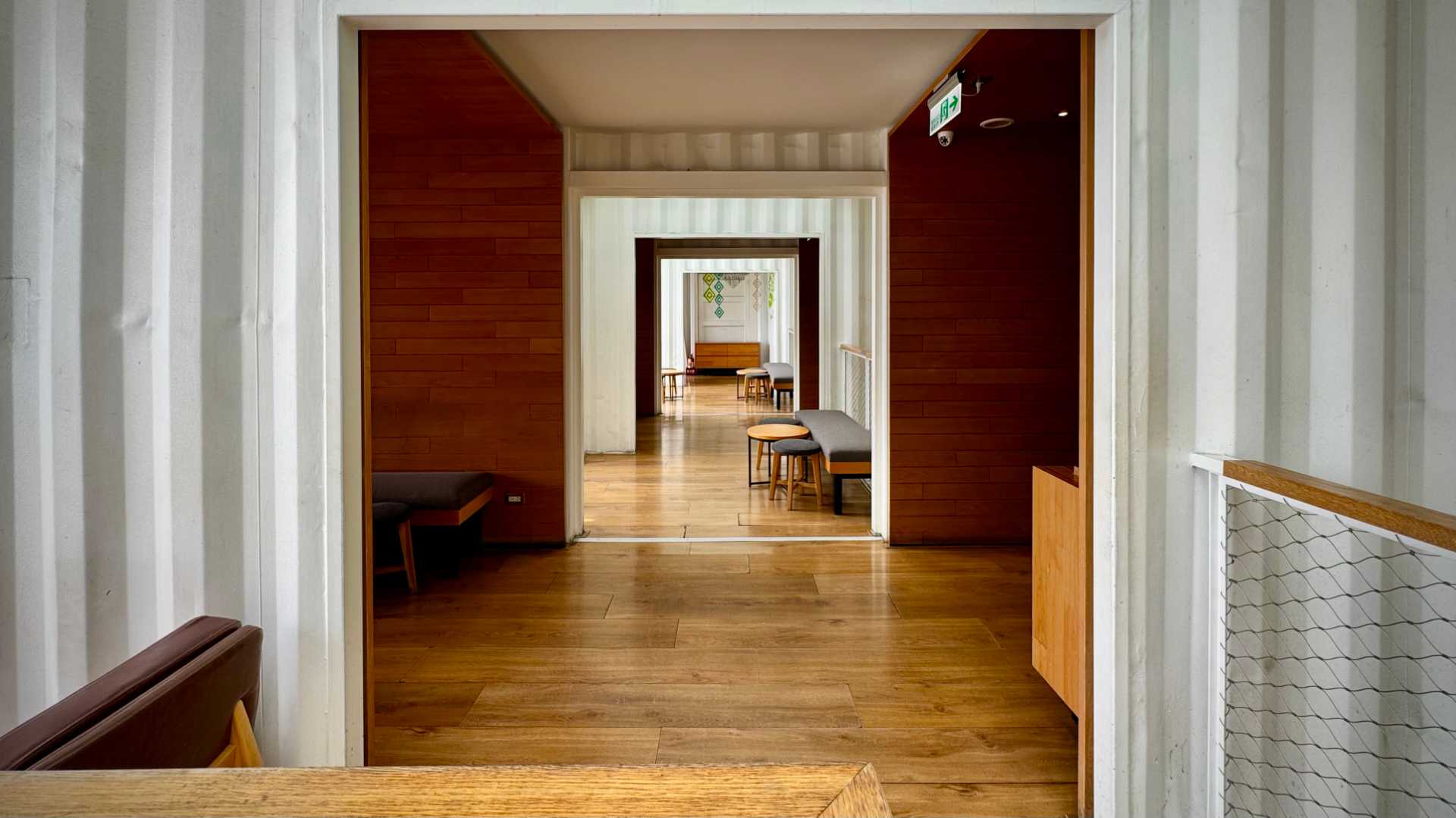 Interior of a shipping container Starbucks, showing wooden floors and a mix of wood-paneled and exposed metal walls.