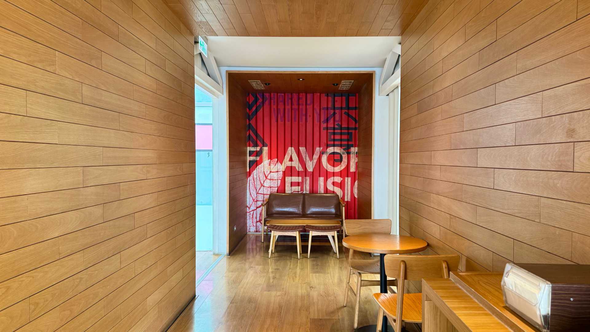 A two-seater leather couch in a small nook, with the words ‘flavor’ and ‘fusion’ on a bold mural behind it.
