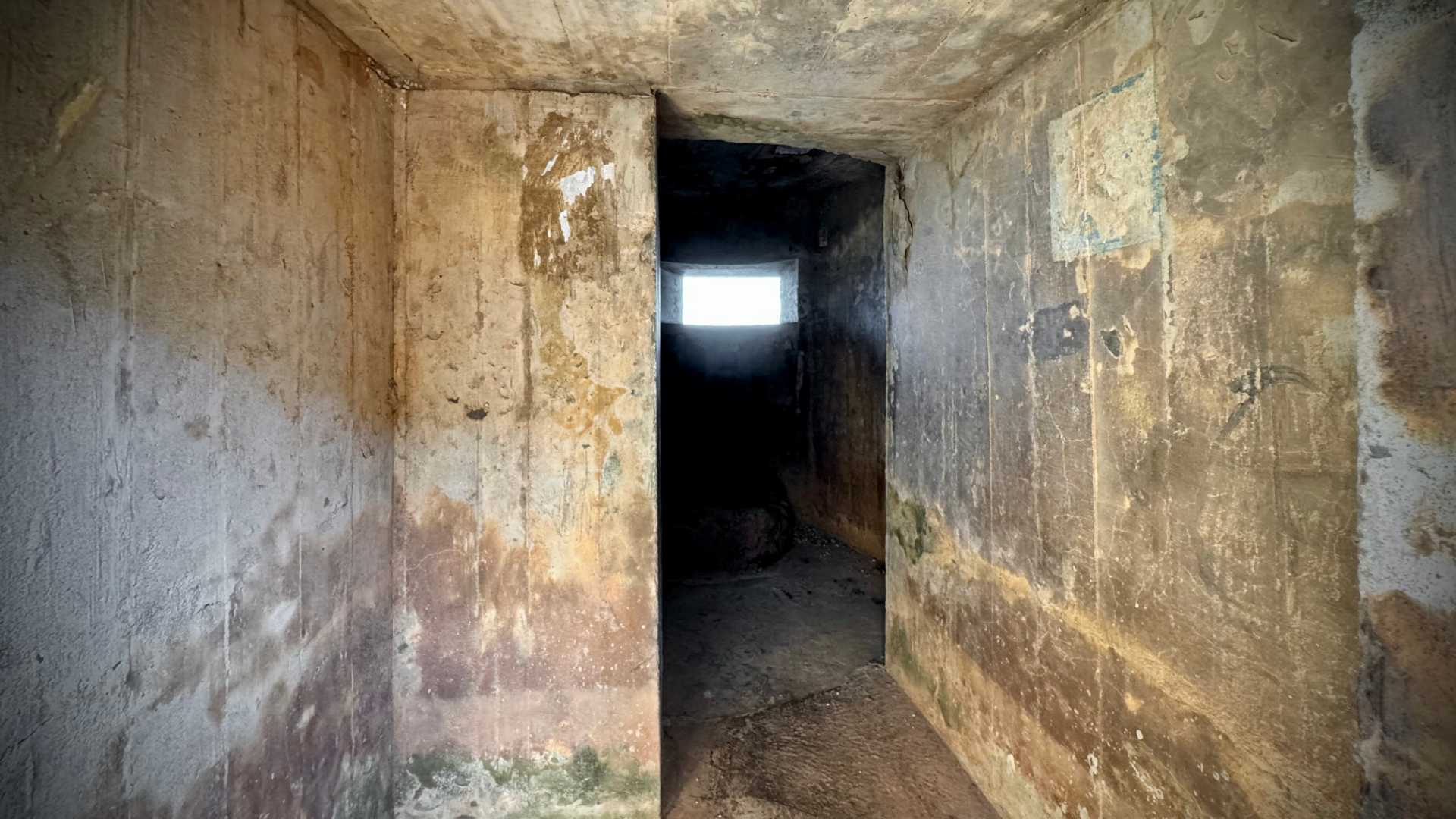 Wide-angle view of the inside of a concrete bunker-like pillbox.