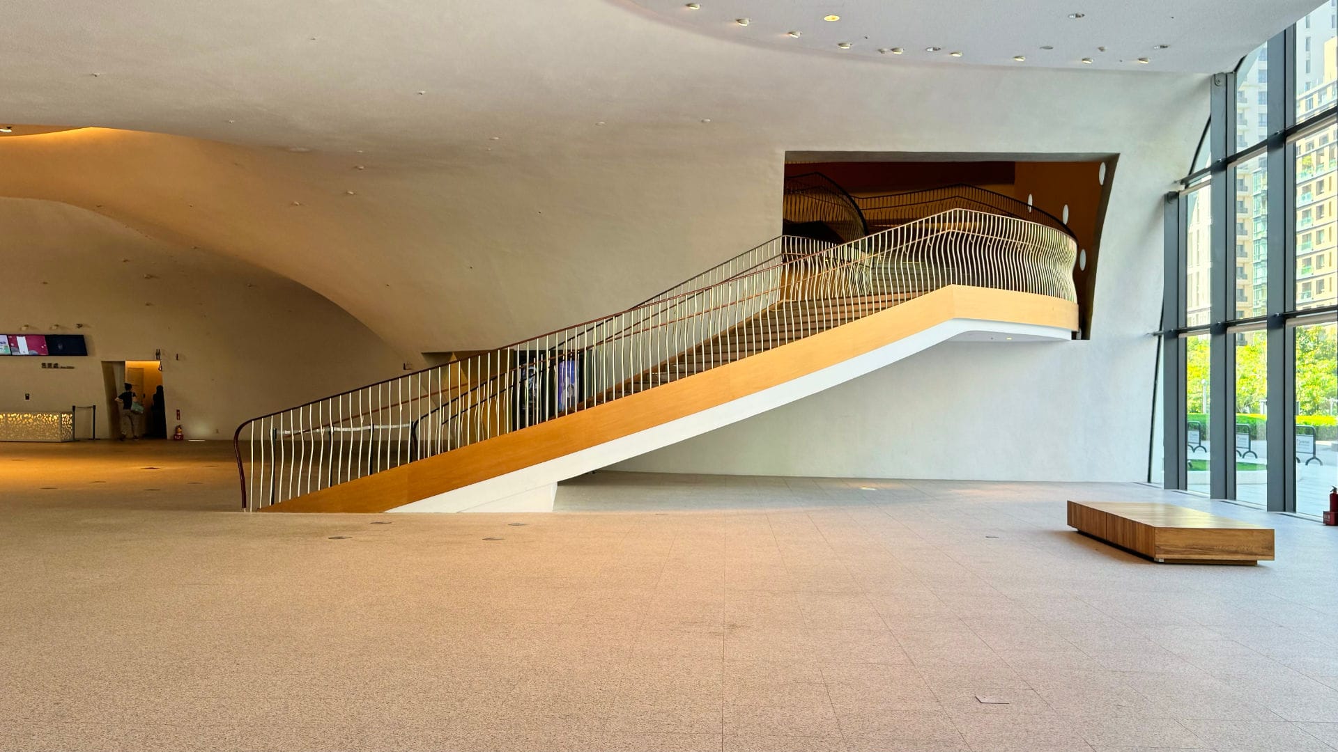 A wide curved staircase descending from a cave-like opening of an interior wall.