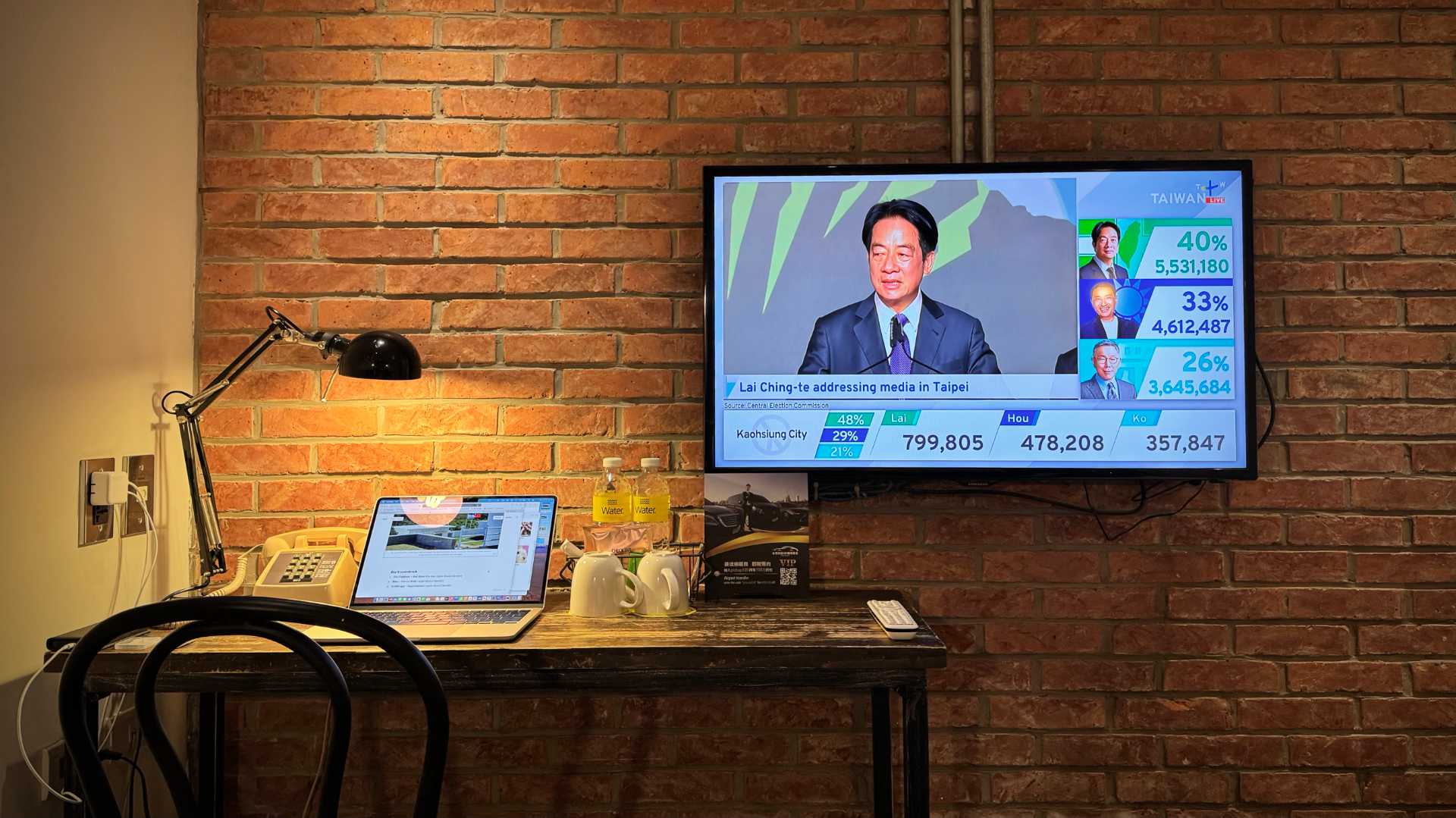 Photo of a TV in a hotel room, above a desk. The TV is displaying TaiwanPlus coverage of the 2024 Taiwan presidential election. President-elect Lai Ching-Te is speaking. To the right of the screen, the results show he has 40% of the vote, with his opponents having 33% and 26%.