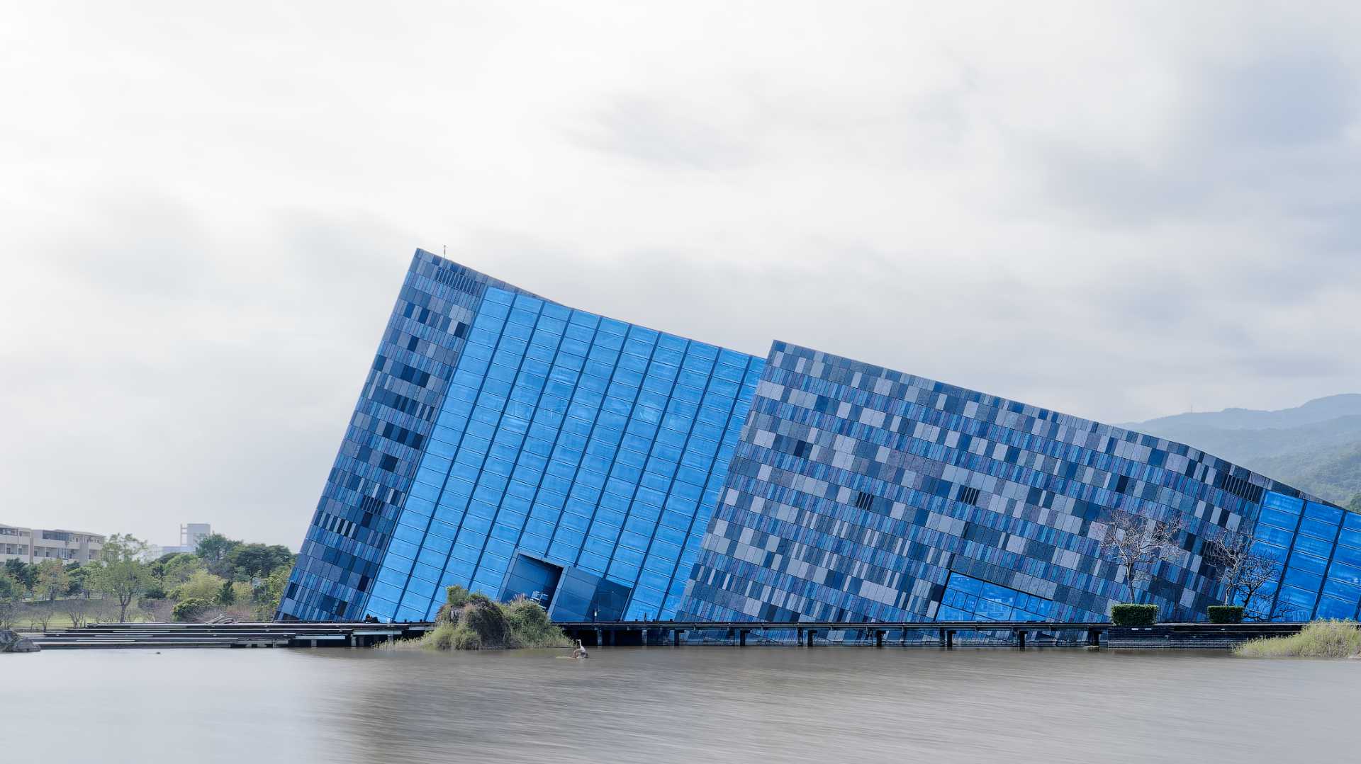 Lanyang Museum, an unconventional glass-and-tile building that appears to be sinking into a lake. Because of it’s partially-sunken appearance, it’s hard to estimate the size of the building. It appears to be a few stories tall at the highest point.