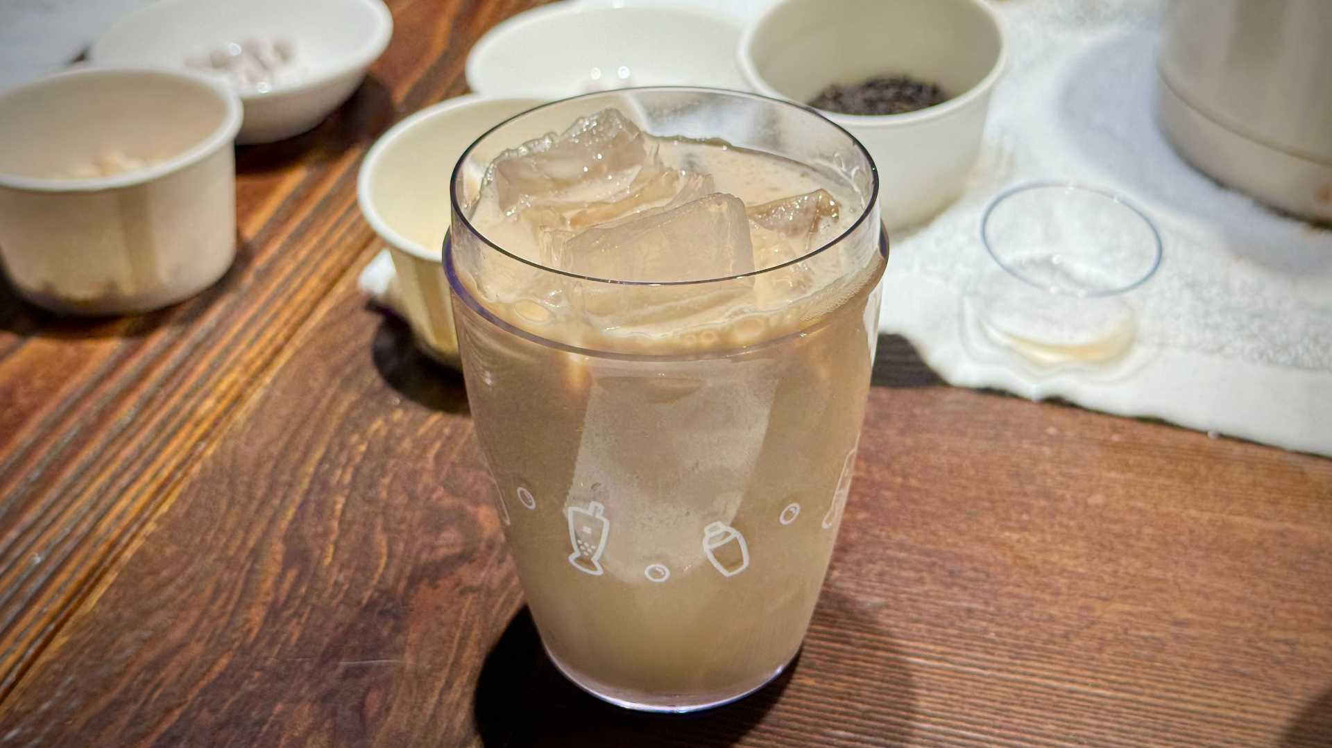A transparent plastic cocktail shaker containing milk tea and ice.