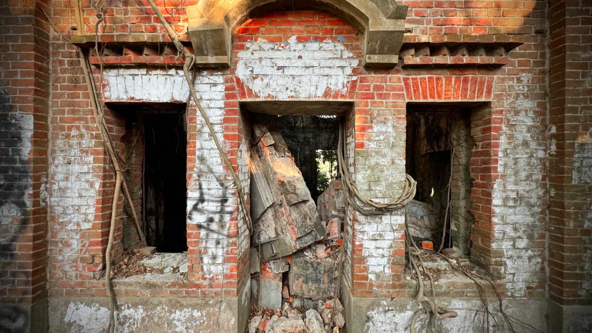 Close-up of the entranceway of Minxiong Haunted House. The doors and windows are missing. The doorway is filled with rubble.