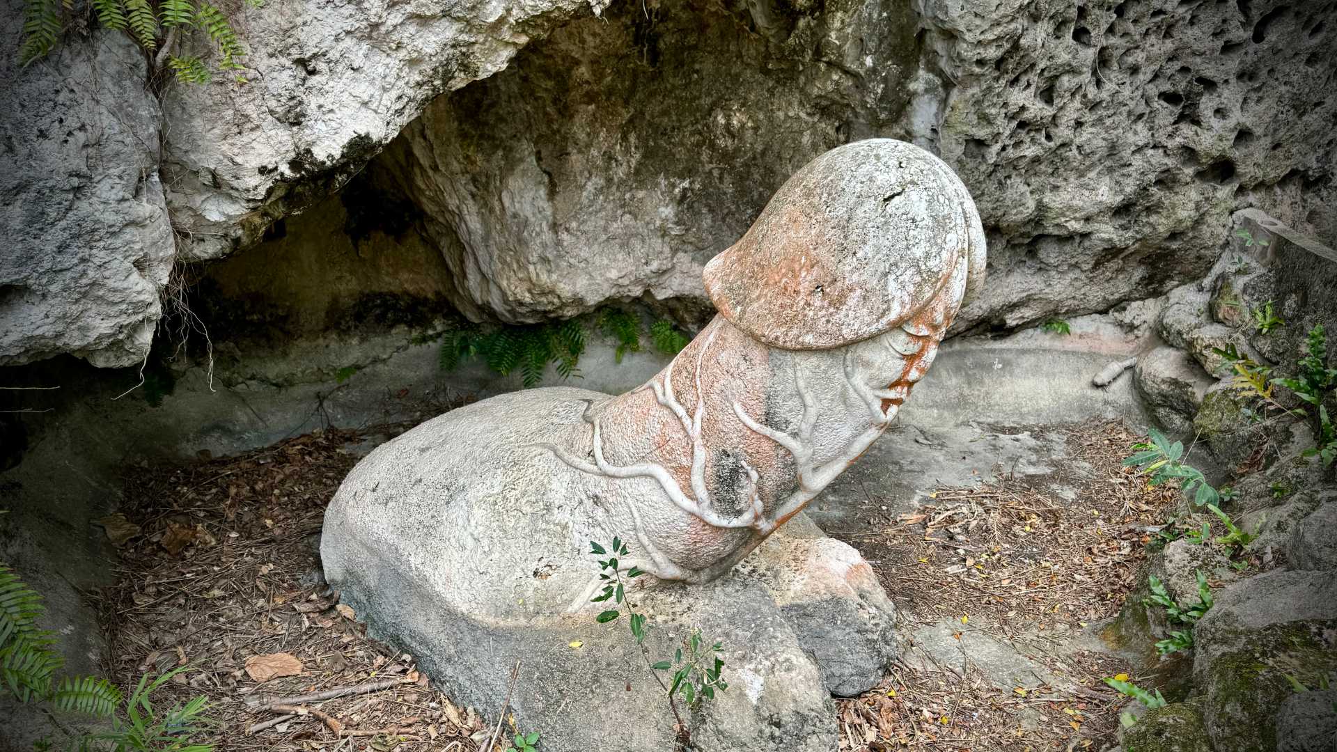 A large stone sculpture of an erect penis, inside a cave.