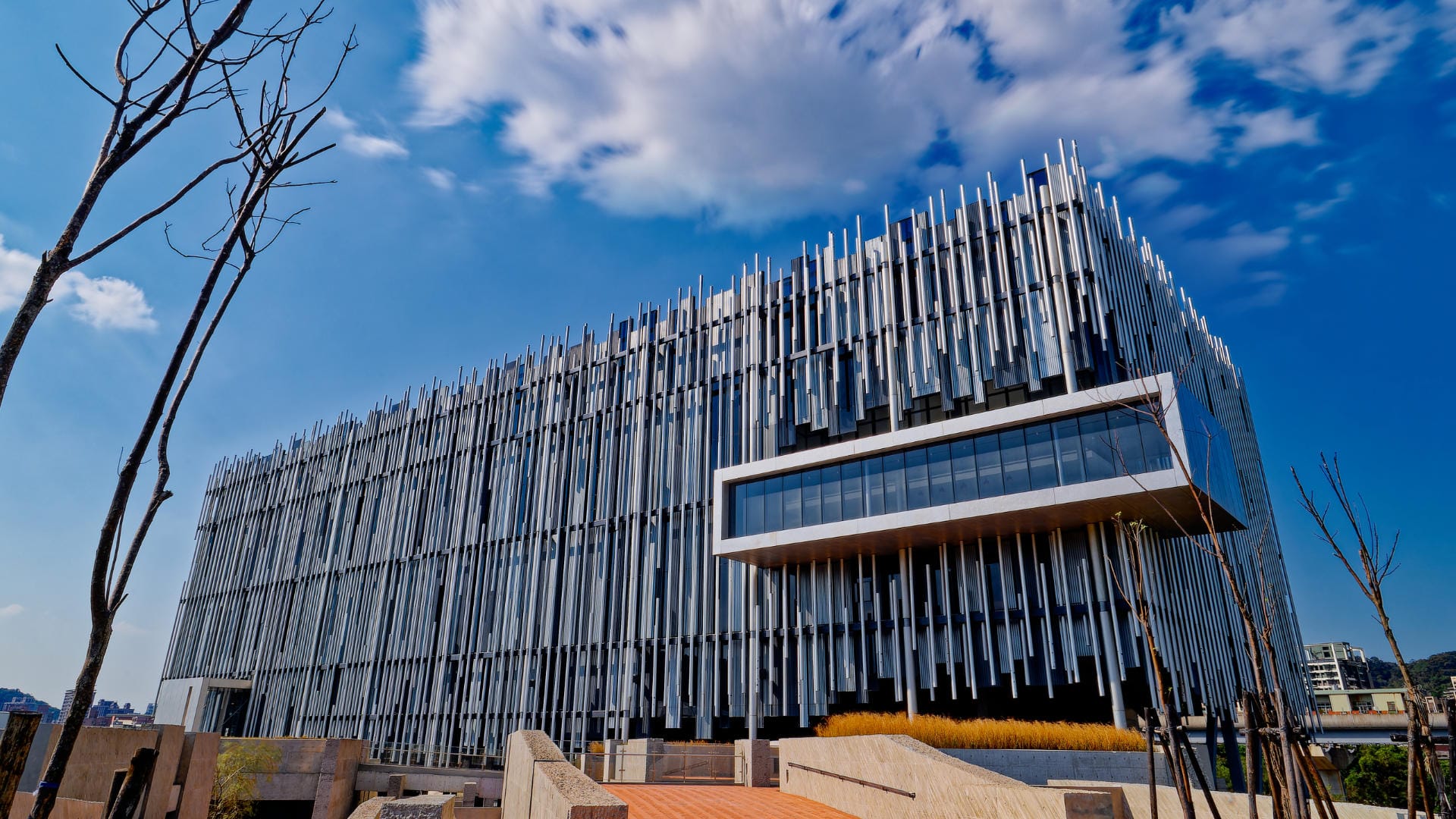 Long exposure of the New Taipei City Art Museum, an avant-garde multi-story building that looks like a rectangular box clad in vertical round metal pipes.