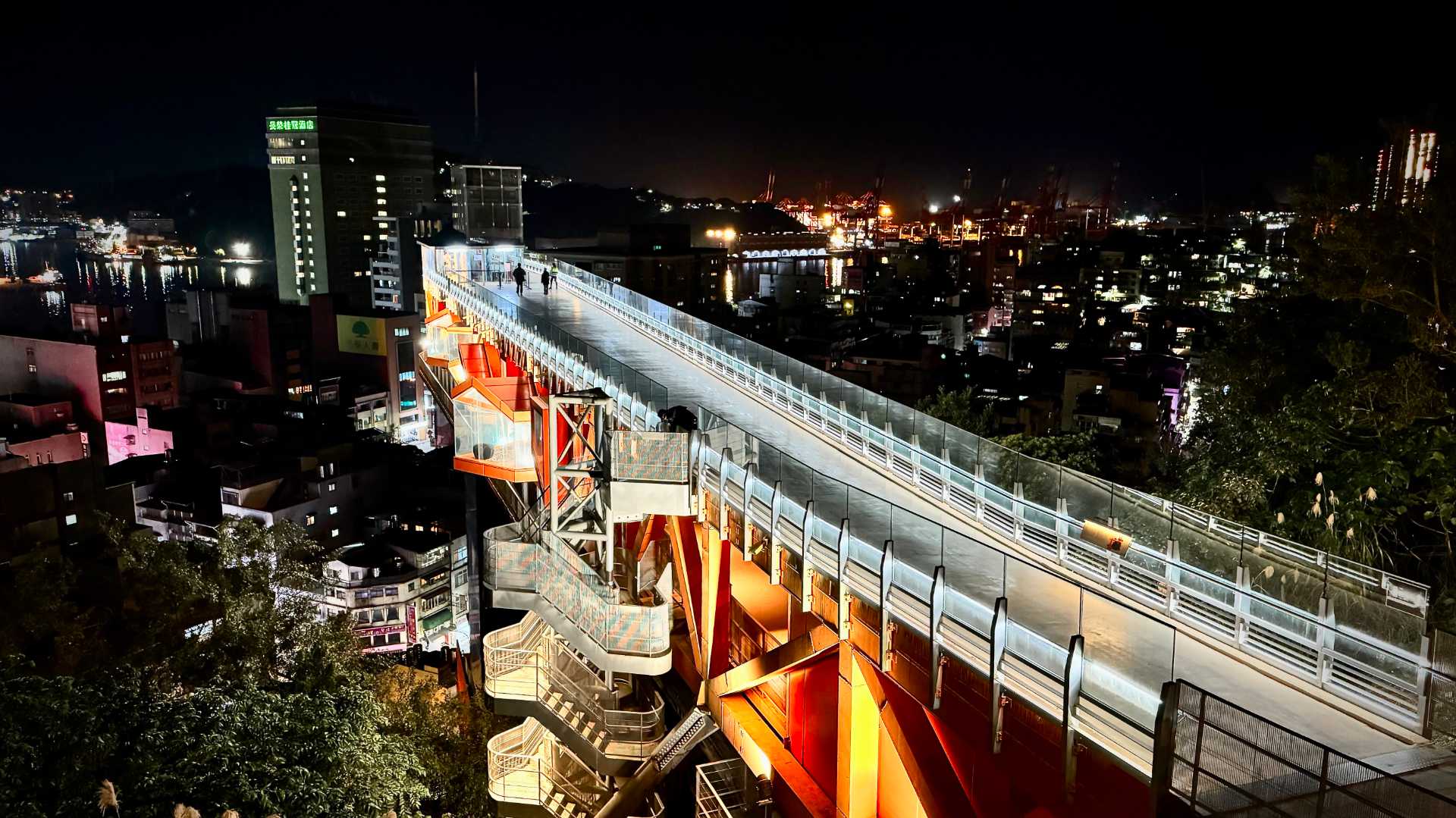 A nighttime view looking down on Keelung Tower from a few meters further up the hill. The city is visible in the distance.