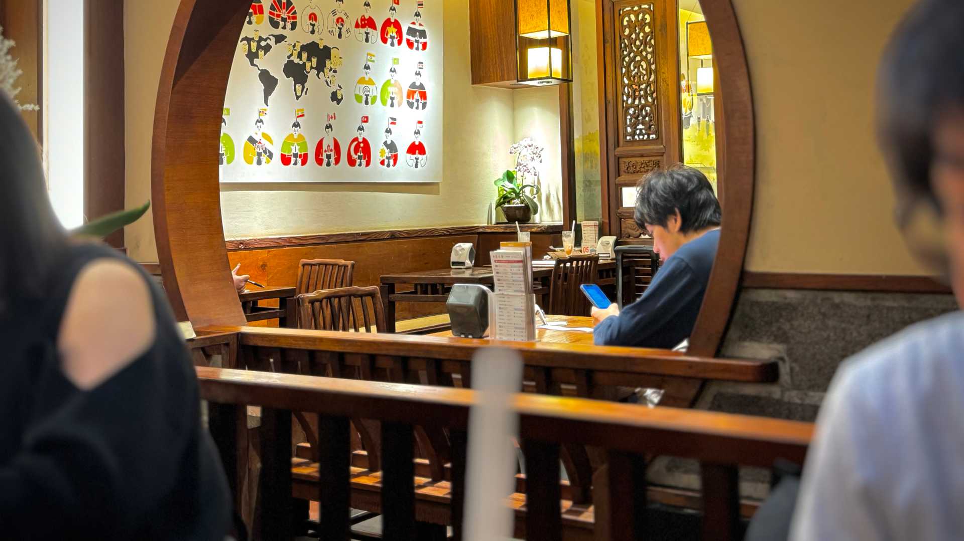 Interior of the original Chun Shui Tang teahouse. A customer sits at a table looking at his phone.