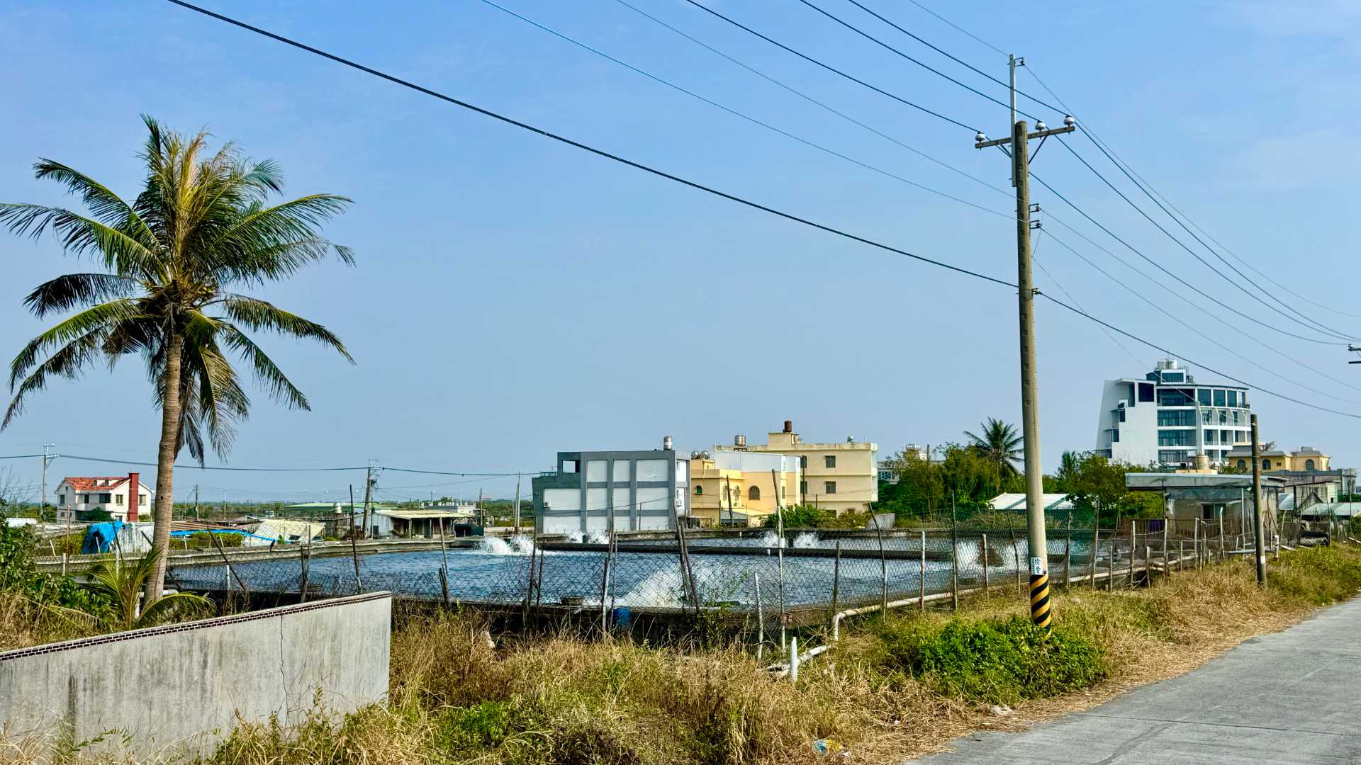 Water being aerated in a raised fish farm next to a country road.