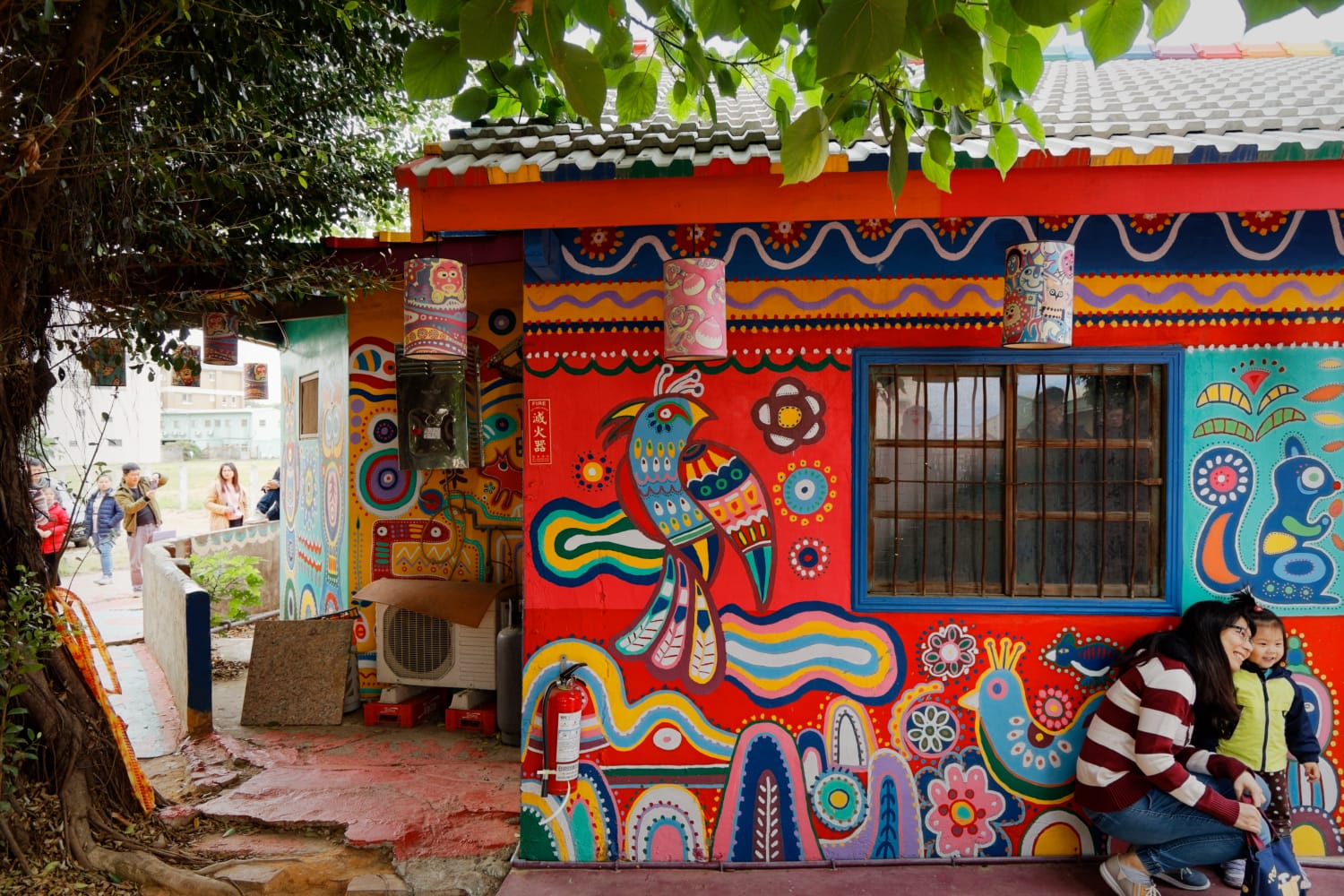 A mother and daughter pose for photos outside a brightly-painted house in Rainbow Village, Taichung, Taiwan.