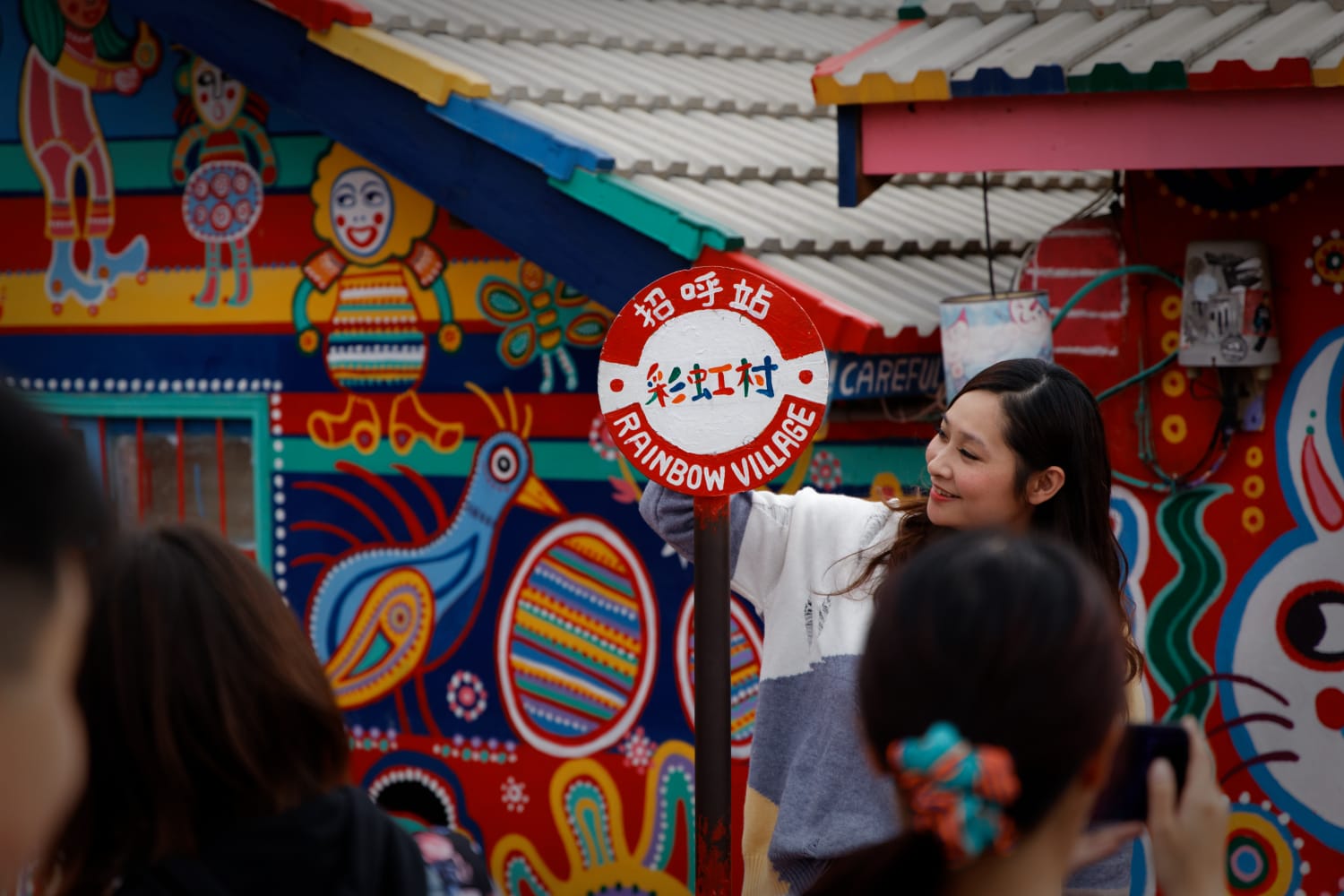 Outside the entrance to Rainbow Village in Taichung, Taiwan, a woman looks at the village sign.