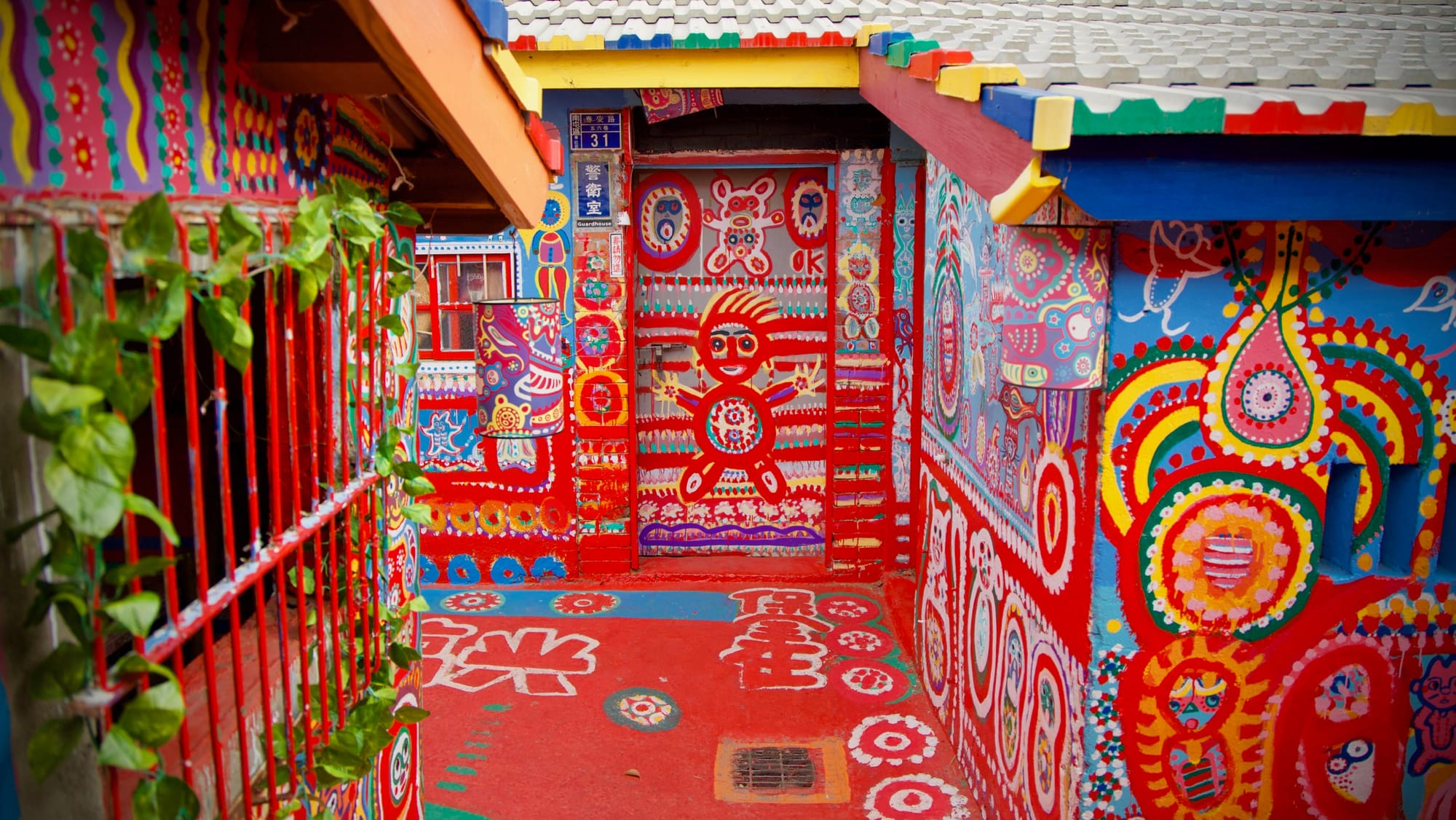 A house with street number 31 in Rainbow Village. The walls of the house, and the ground, are brightly painted with abstract art.
