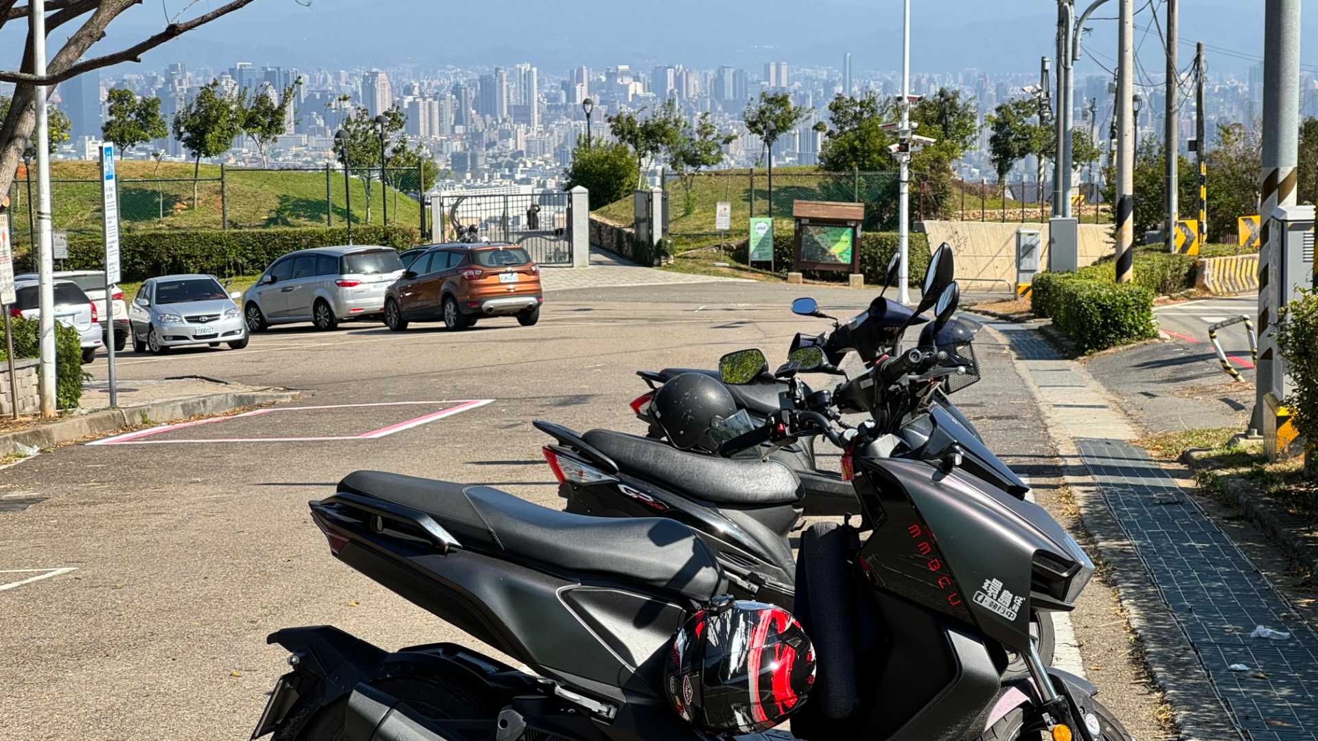 An SYM MMBCU scooter parked on a hill, with a view of Taichung City in the background.