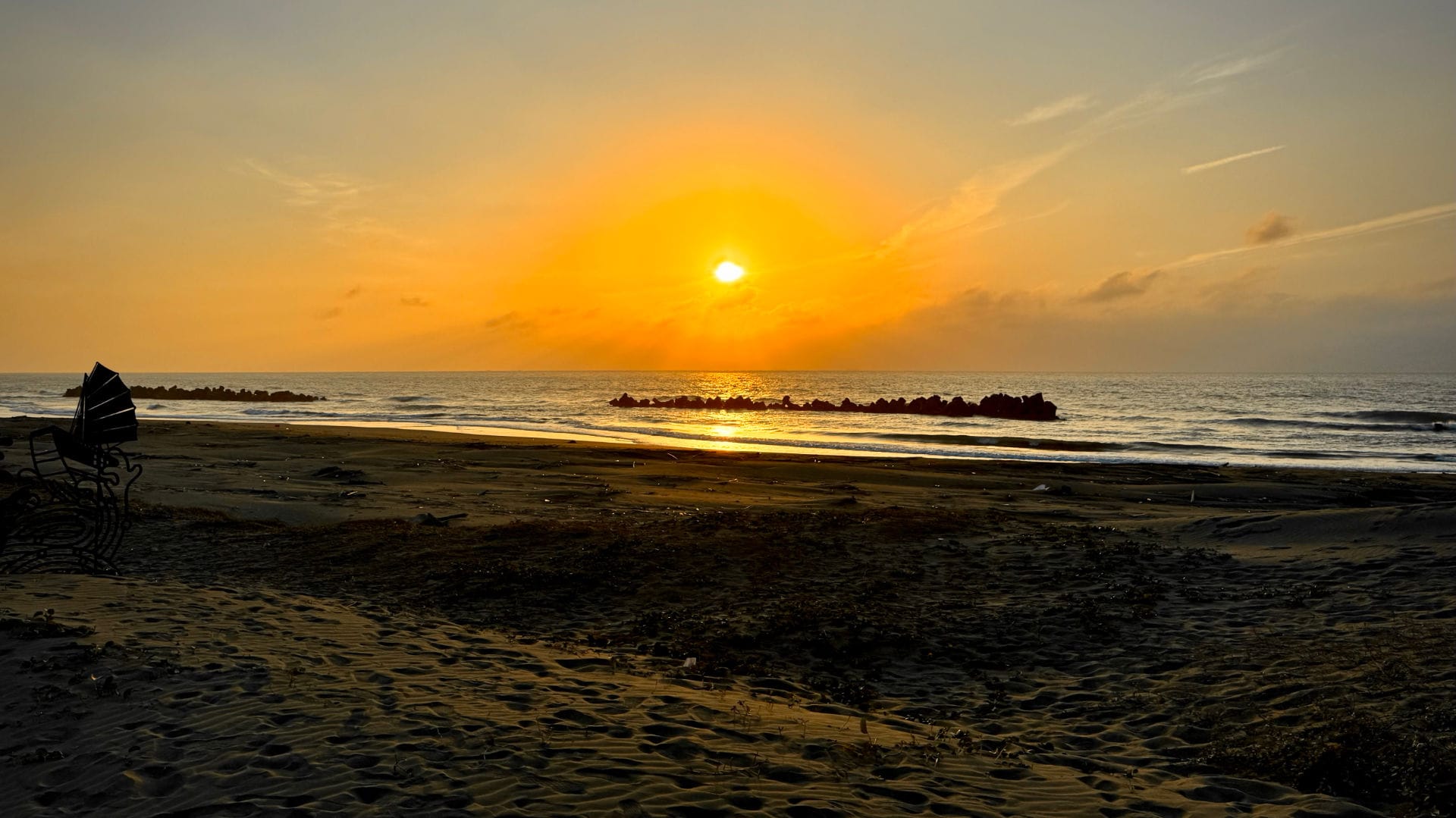 Sun setting over the Strait of Taiwan with a beach in the foreground.