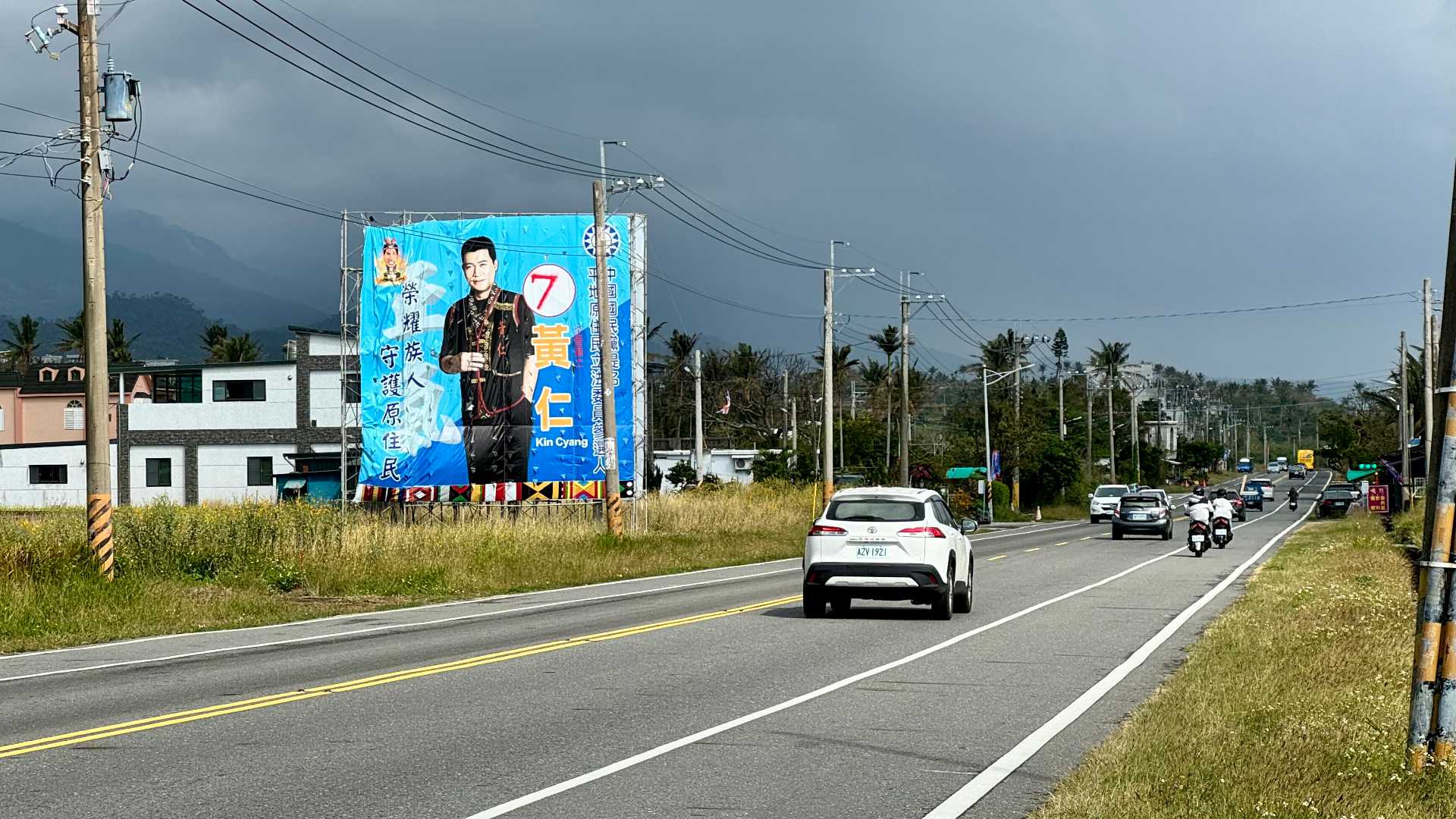 A large election billboard next to a four-lane road in the countryside.