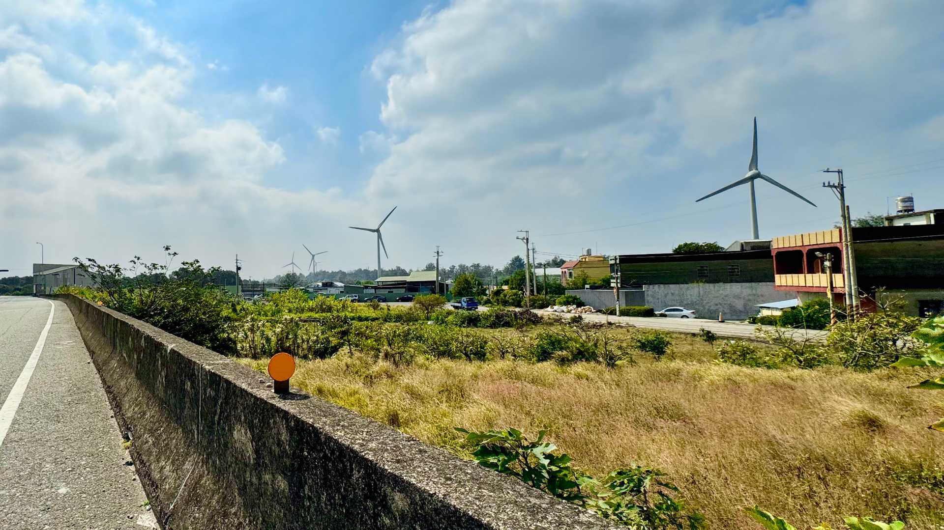 Five wind turbines in a rural area of Taiwan, viewed from the side of a road.