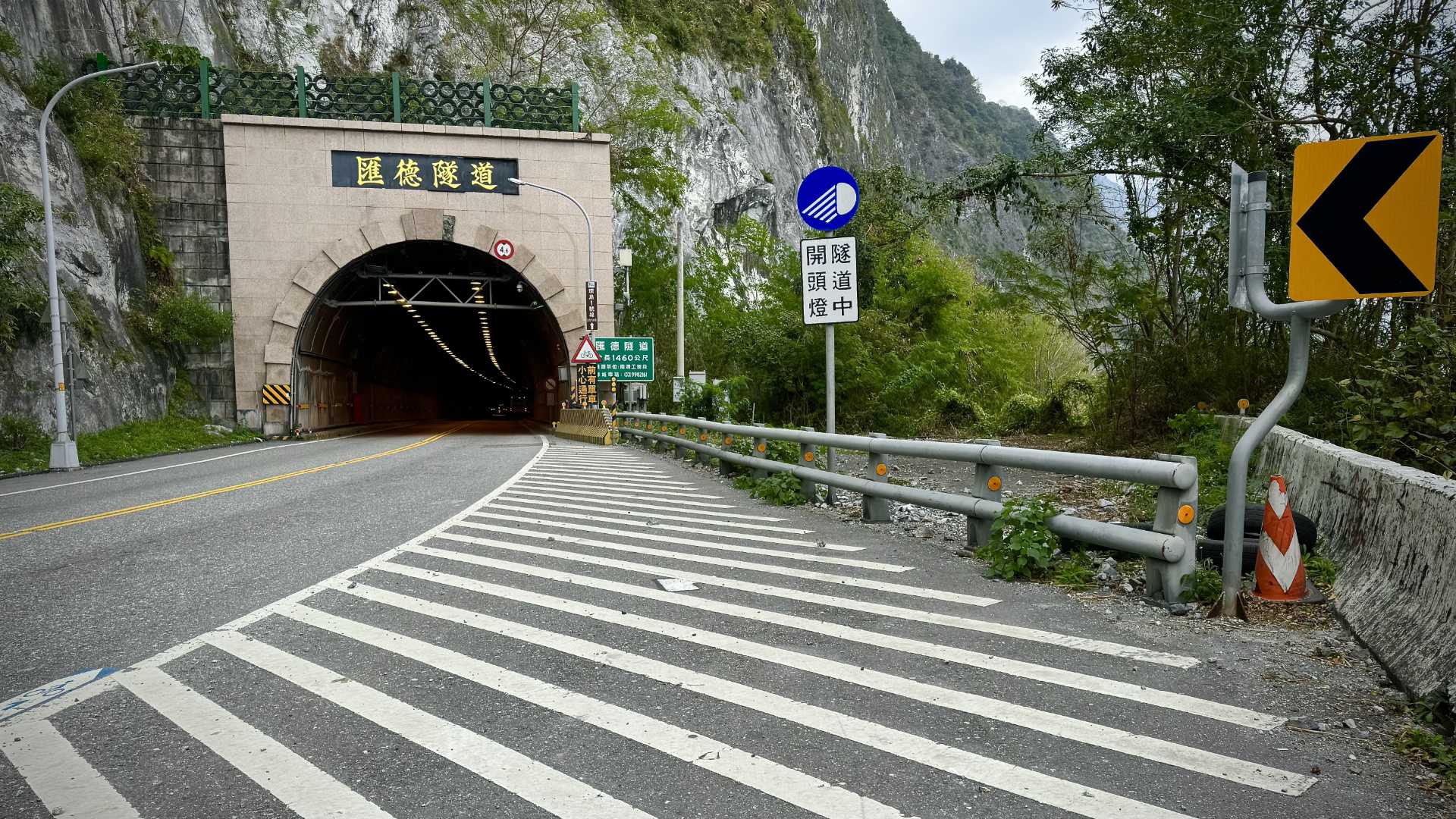 The entrance to a two-lane road tunnel through a mountain.