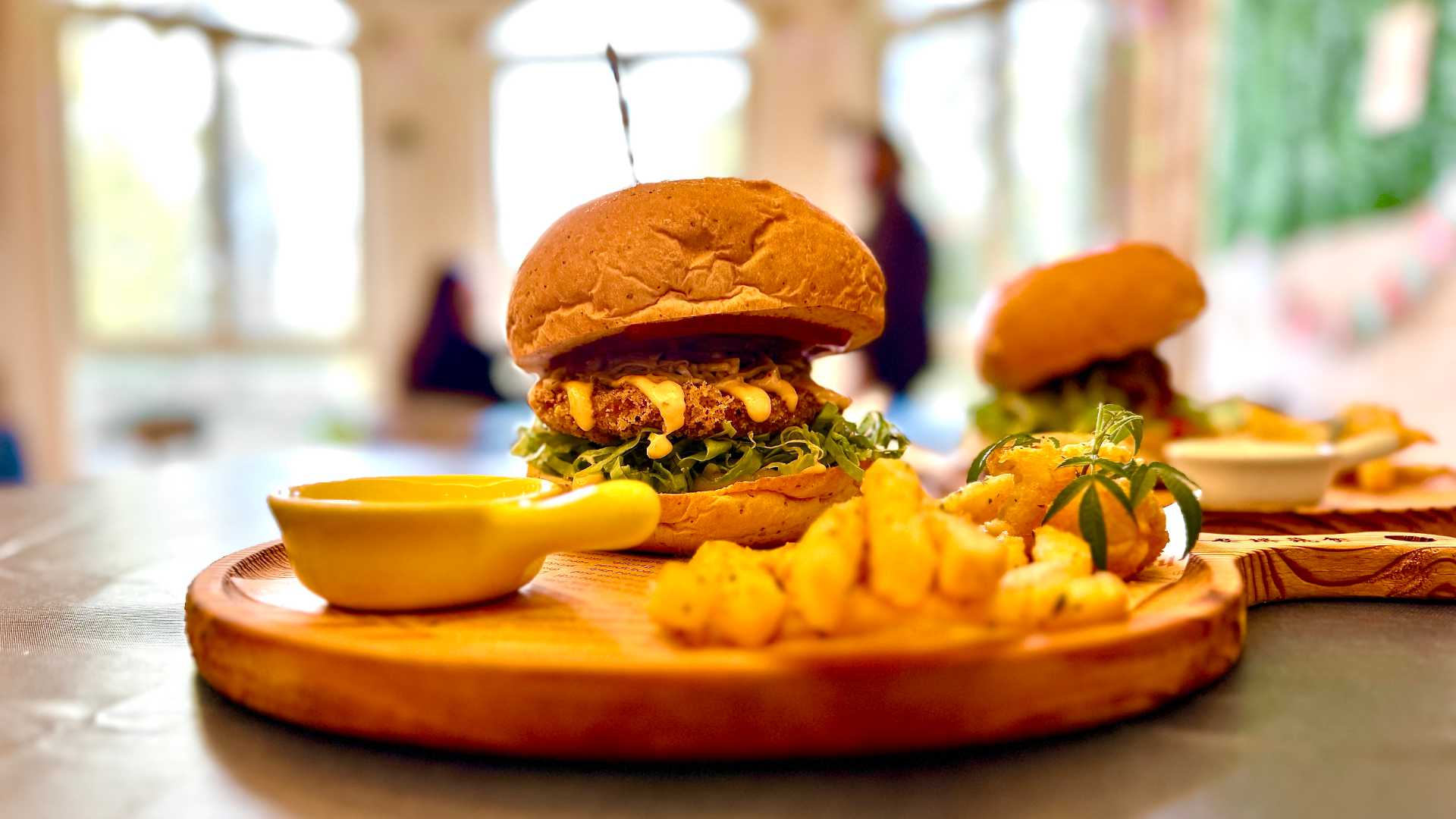 Close-up of a vegetable burger served on a round wooden tray with a side of potato fries.