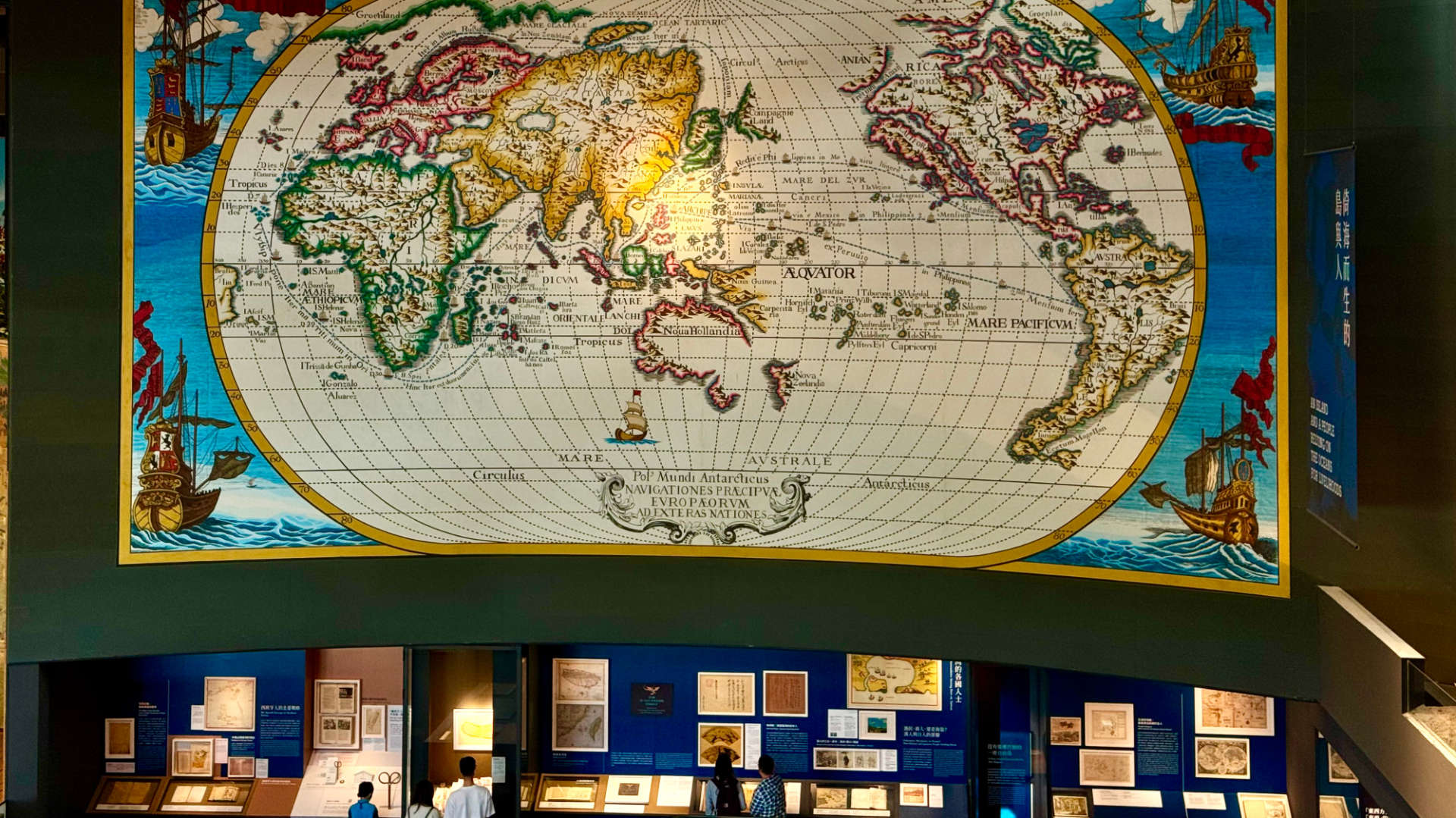 An enormous reproduction of a historic world map, painted on a wall inside the National Museum of Taiwan History. The map may be around 10 meters tall and 15 or 20 meters wide. A spotlight is shining on ‘Formosa’.