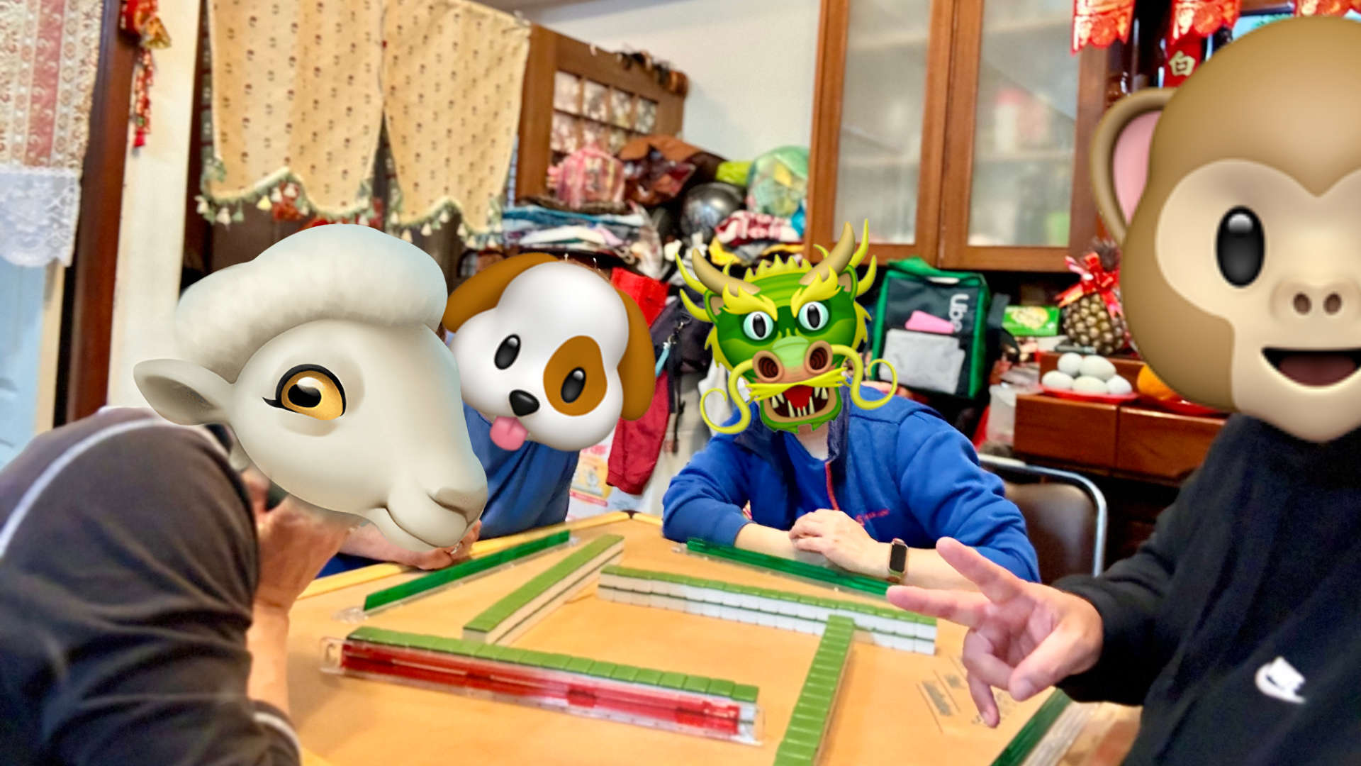 Four people playing mahjong. Their faces are obscured by sheep, dog, dragon, and monkey emoji.