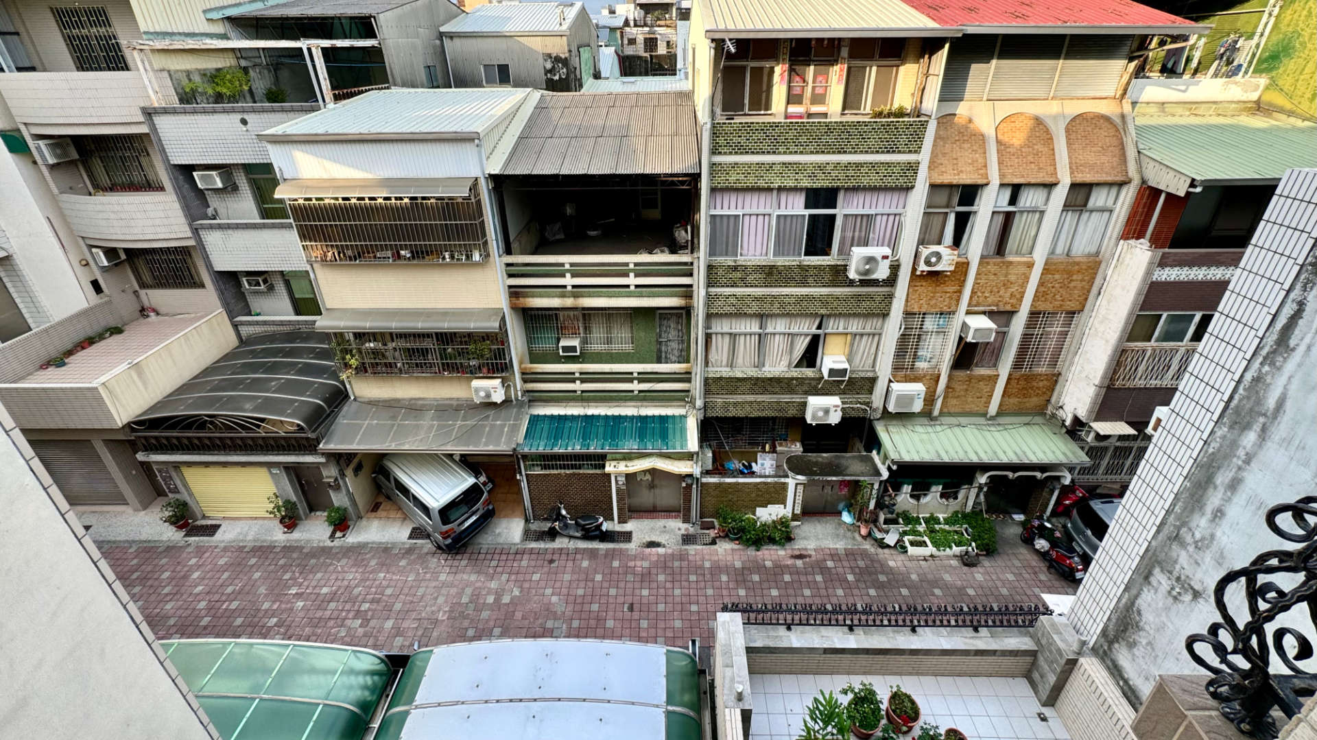A view of townhouses along a narrow street in Tainan, taken from a fourth-floor balcony.