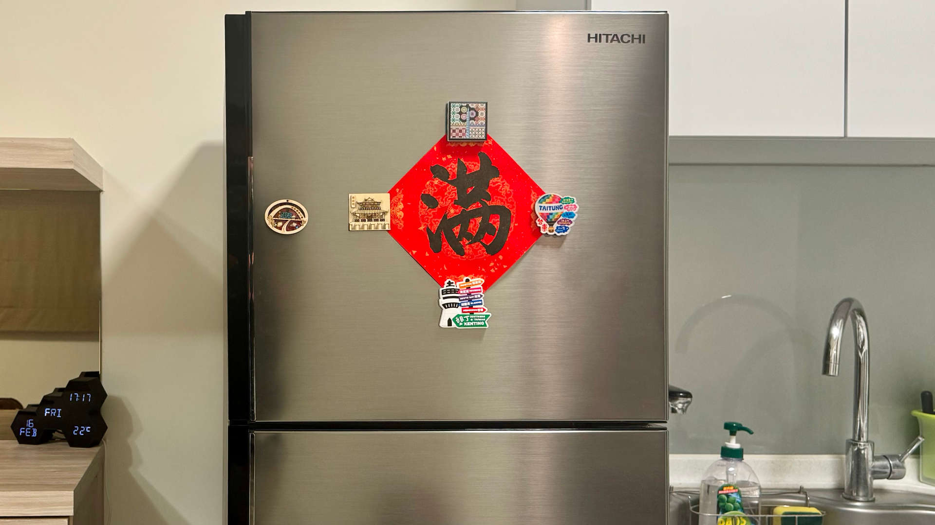 A diamond-shaped piece of paper with a large Chinese character in the middle, affixed to a stainless steel refrigerator by magnets.