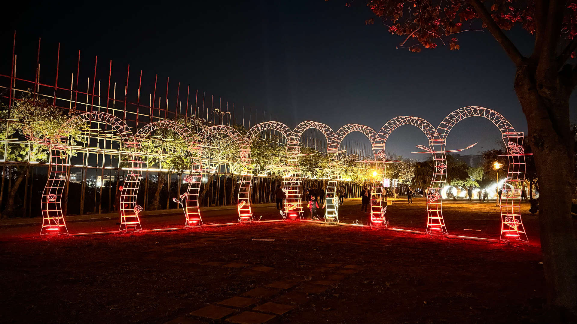 An illuminated sculpture of a series of eight joined wireframe arches arranged in a semi-circle.