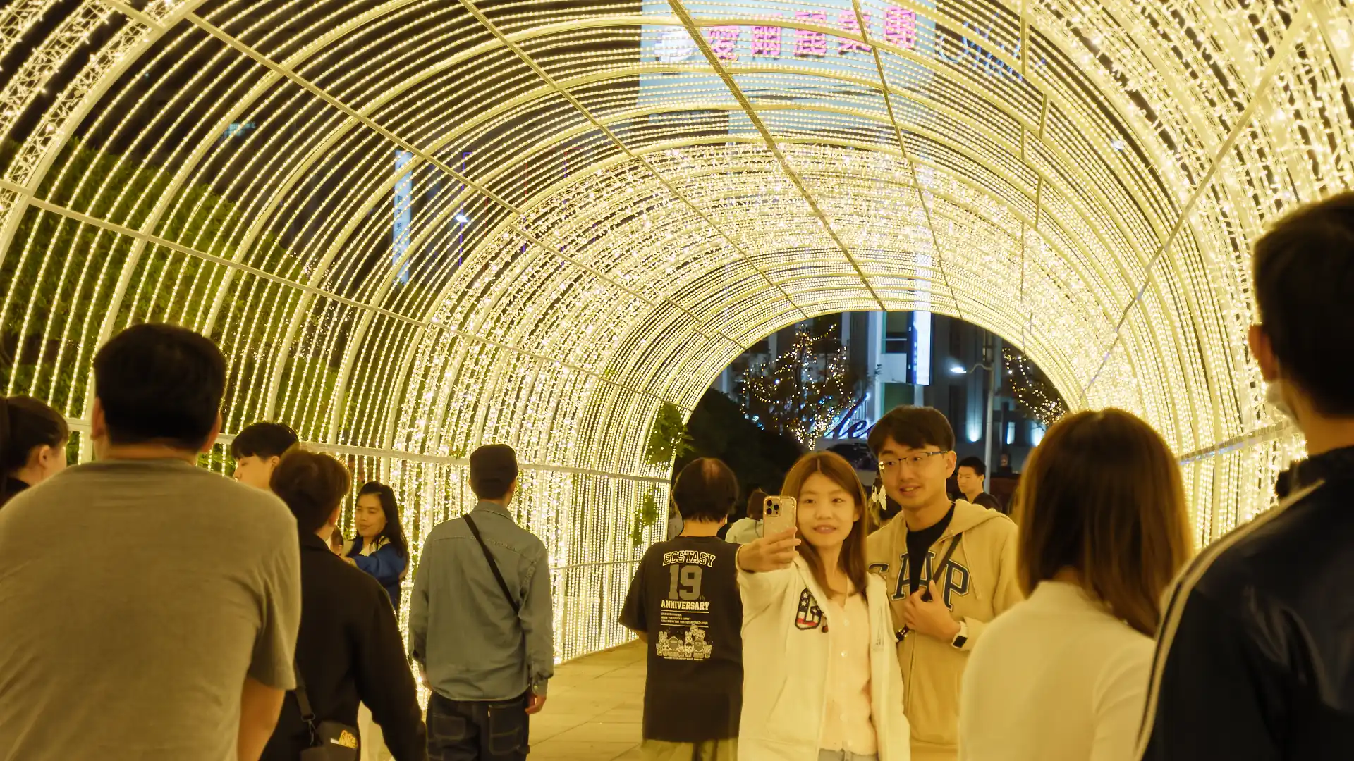 A couple takes a selfie inside a makeshift tunnel of lights.