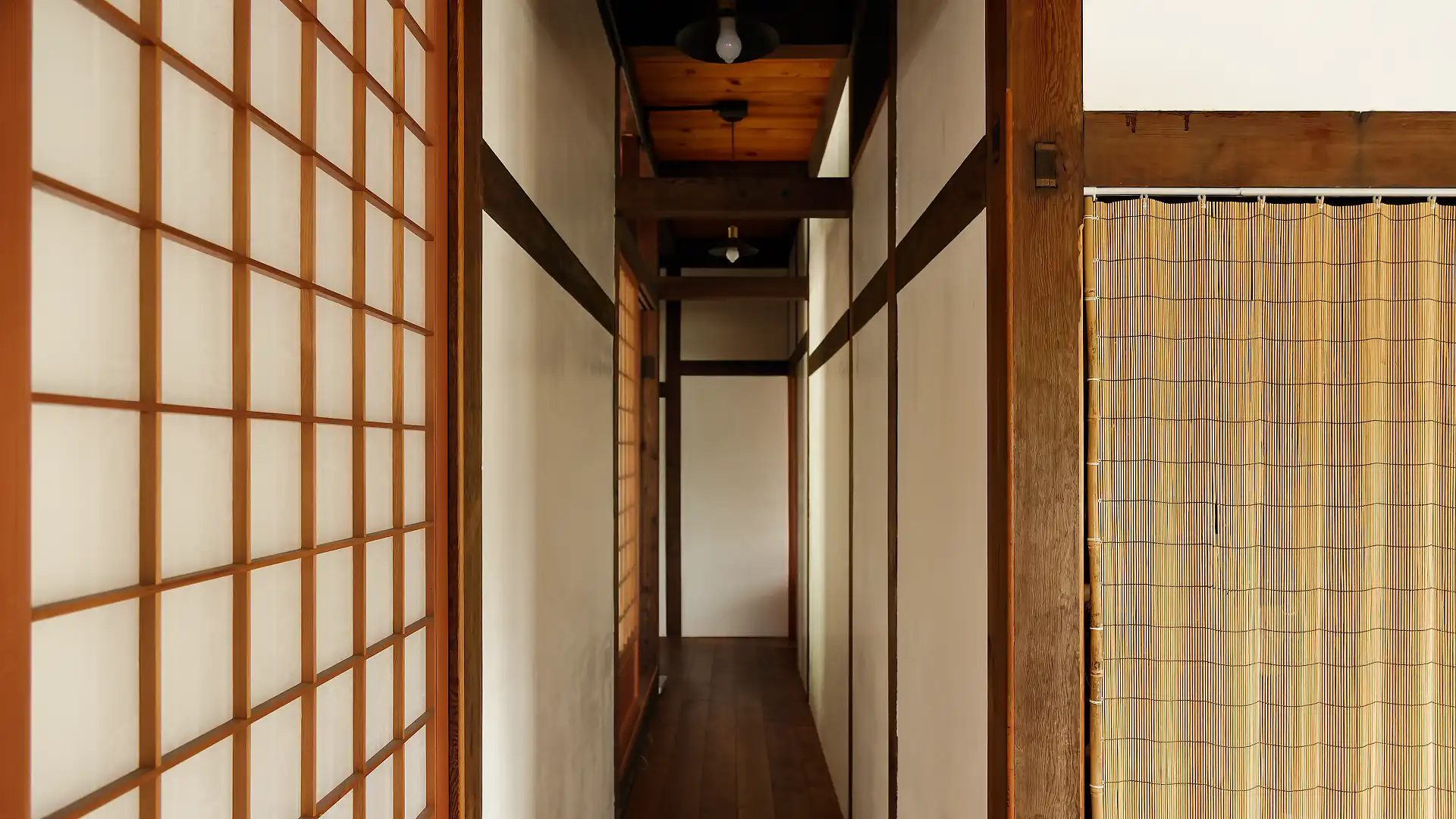 A corridor in ‘A Book Wooden House’, with soft light spilling through shoji screens on the left side.