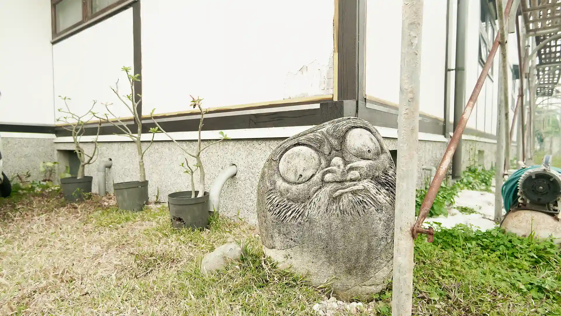 A stone daruma sculpture at the north-east corner of ‘A BooK Wooden House’.