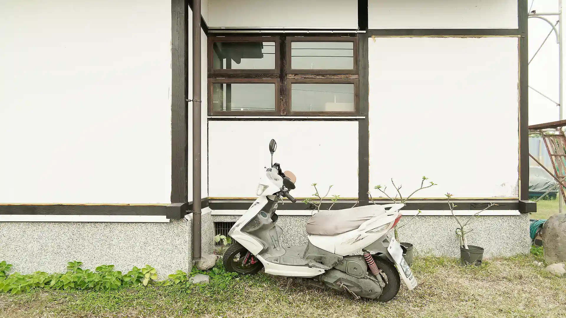 A scooter parked on grass alongside ‘A Book Wooden House’.