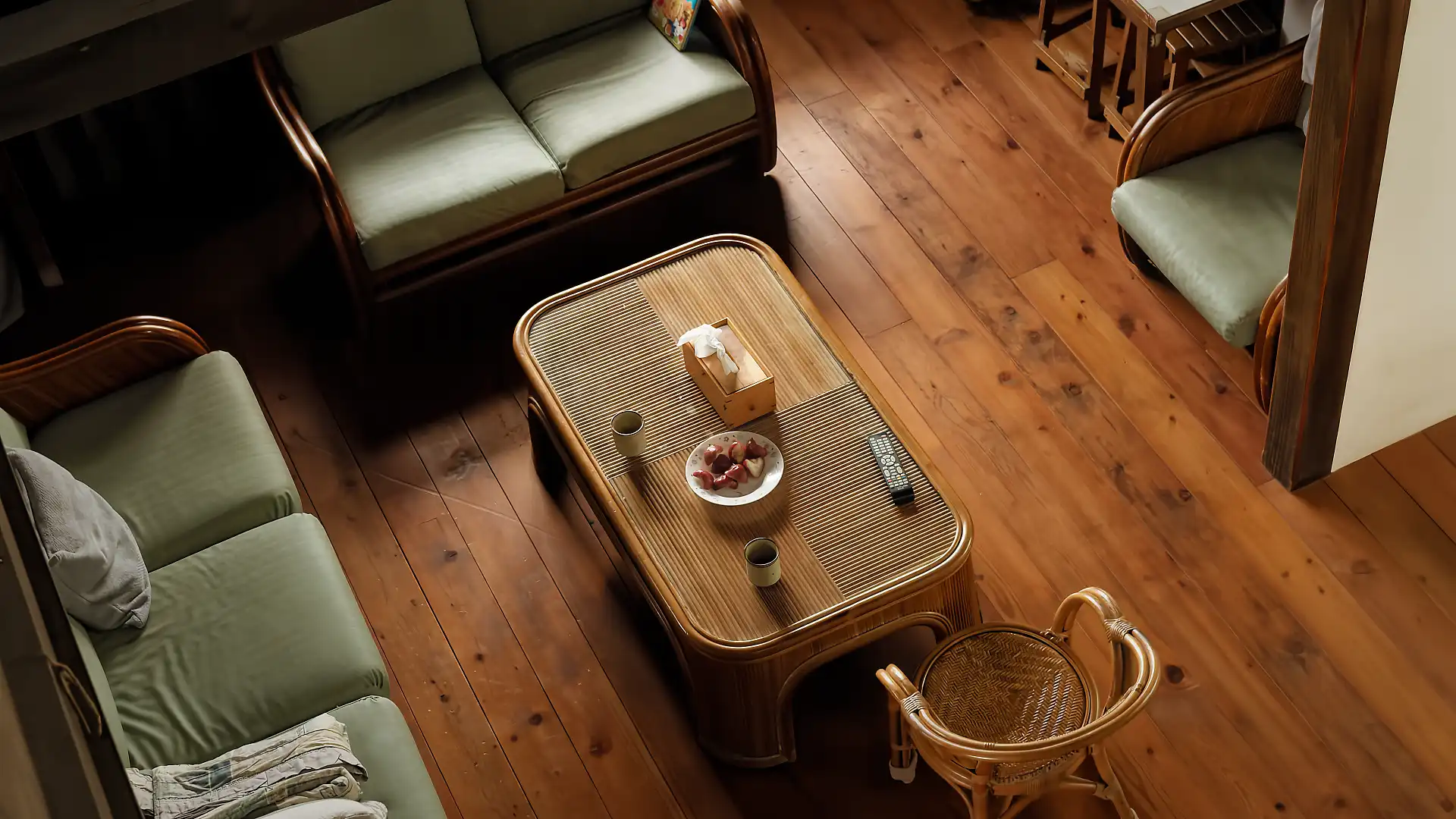 Close-up top-down view of the living room. Two cups of tea and a plate of wax apples are on a coffee table.