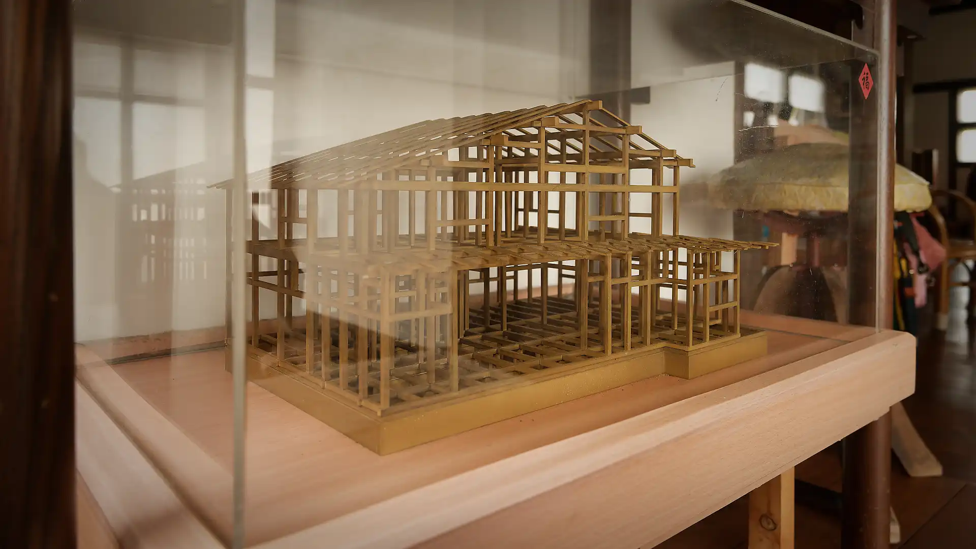 A wooden model of ‘A Book Wooden House’, within a glass case.