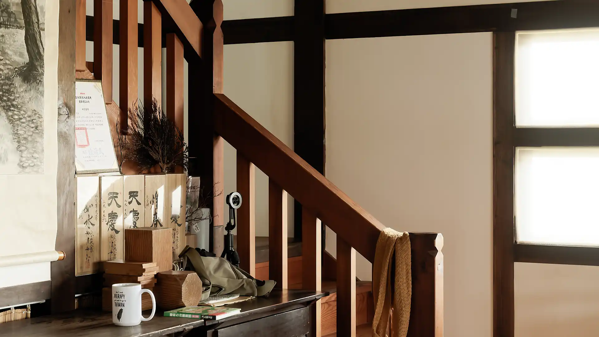 Close-up of decorative items on a side table in front of a wooden staircase.