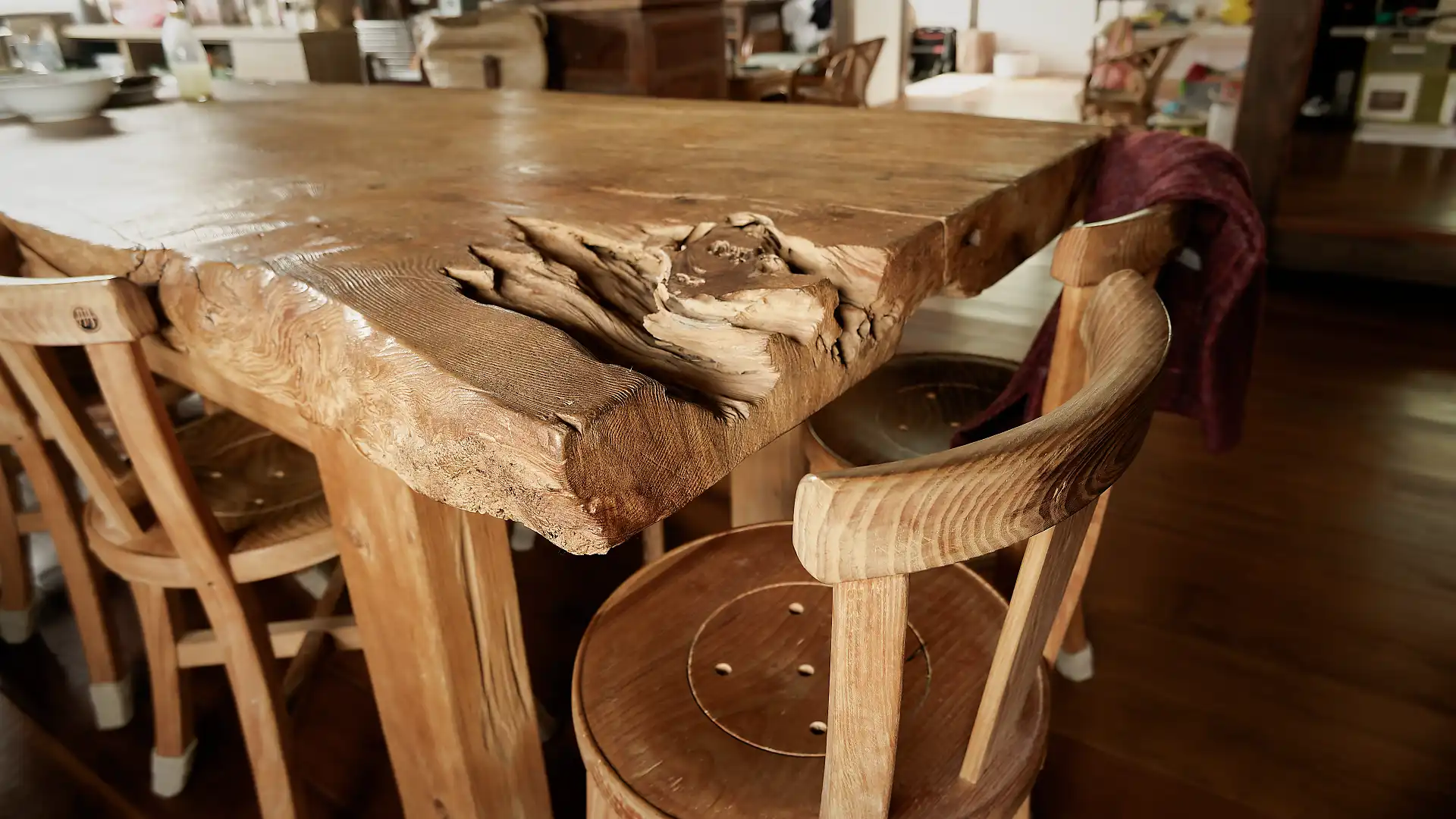 Close-up of one corner of an enormous wooden dining table, crafted from a single tree trunk.