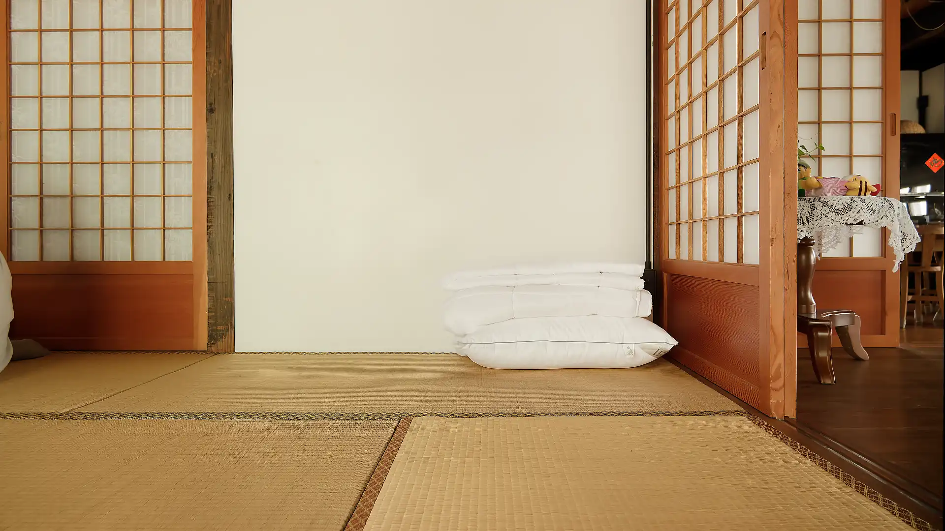 A tatami room with a pillow and duvet folded in one corner.