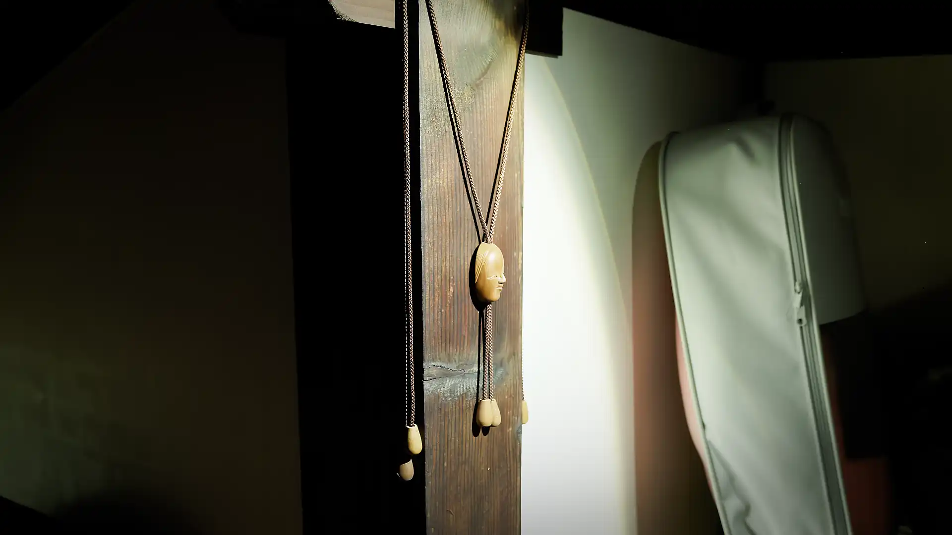A small mask-shaped tchotchke hanging on a wall stud