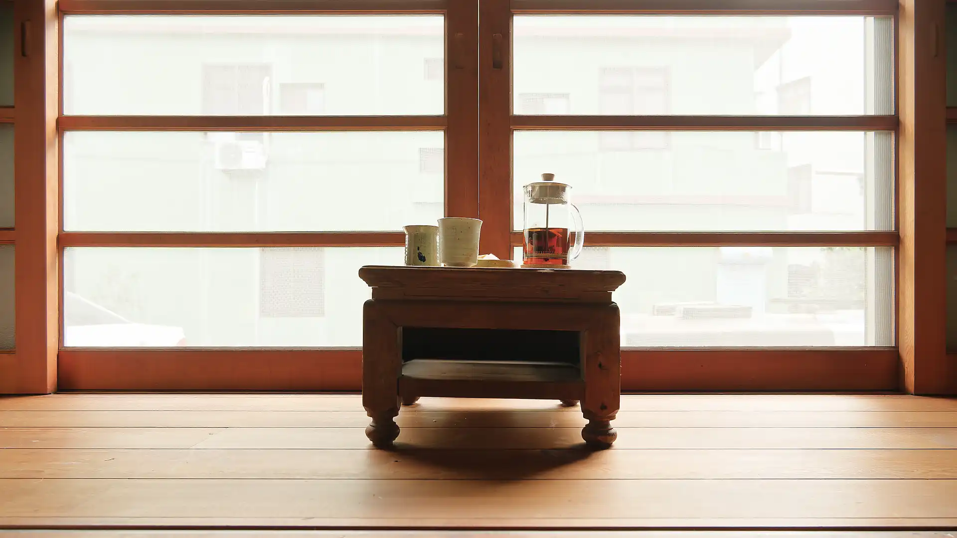 A small wooden side table in front of screen doors.
