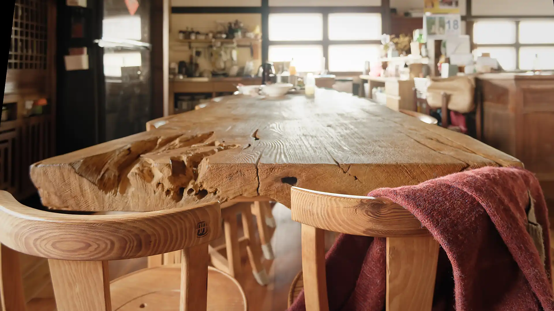Chairs at one end of an enormous wooden dining table, crafted from a single tree trunk.