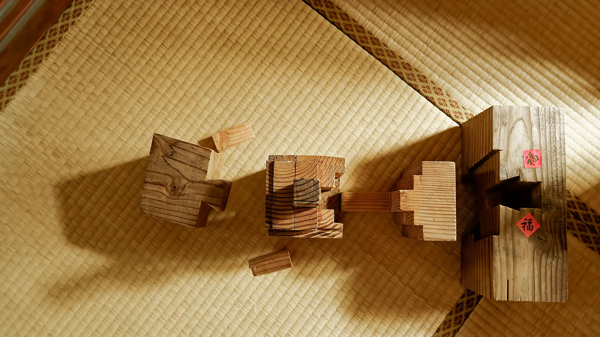 Six irregularly-shaped but precisely-cut blocks of wood, laid out on a tatami mat.