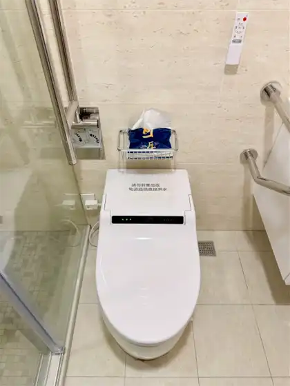 A Karat smart toilet in a Taiwanese bathroom. A candybar-shaped remote control is mounted on the wall behind the toilet.