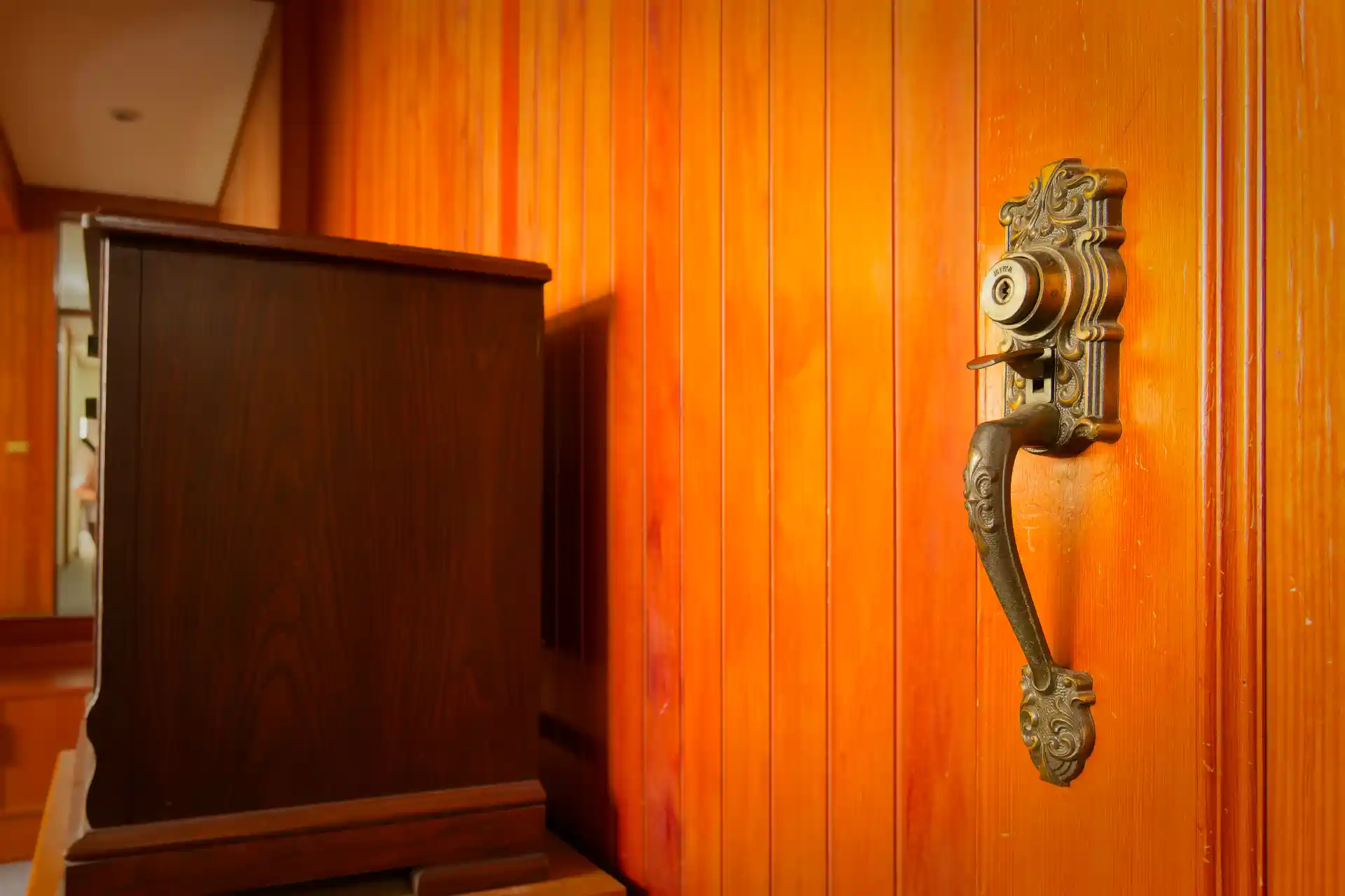 An elaborate metal doorhandle with integrated lock, on an internal wooden door.