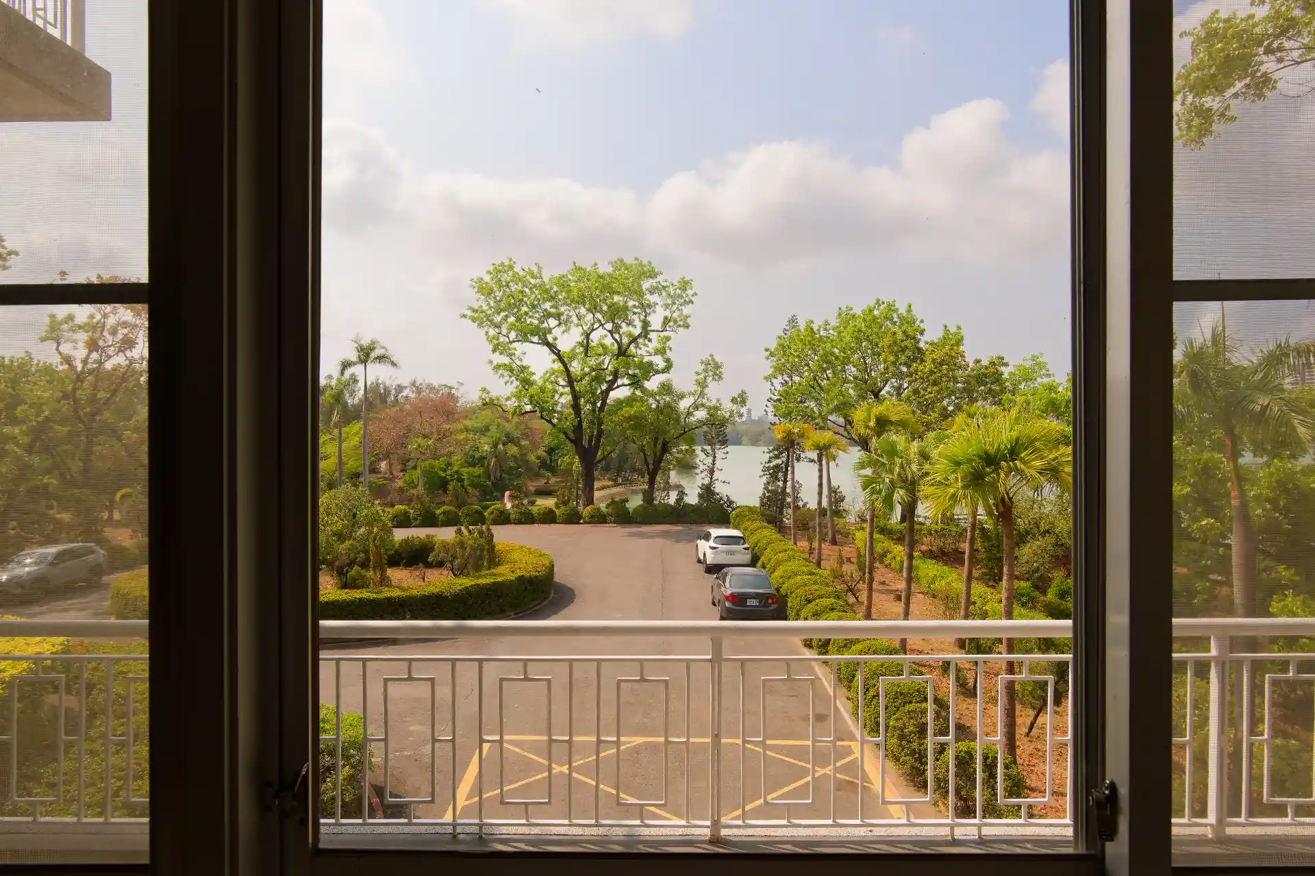 View of a parking lot and an immaculately-maintained garden, with a lake beyond.