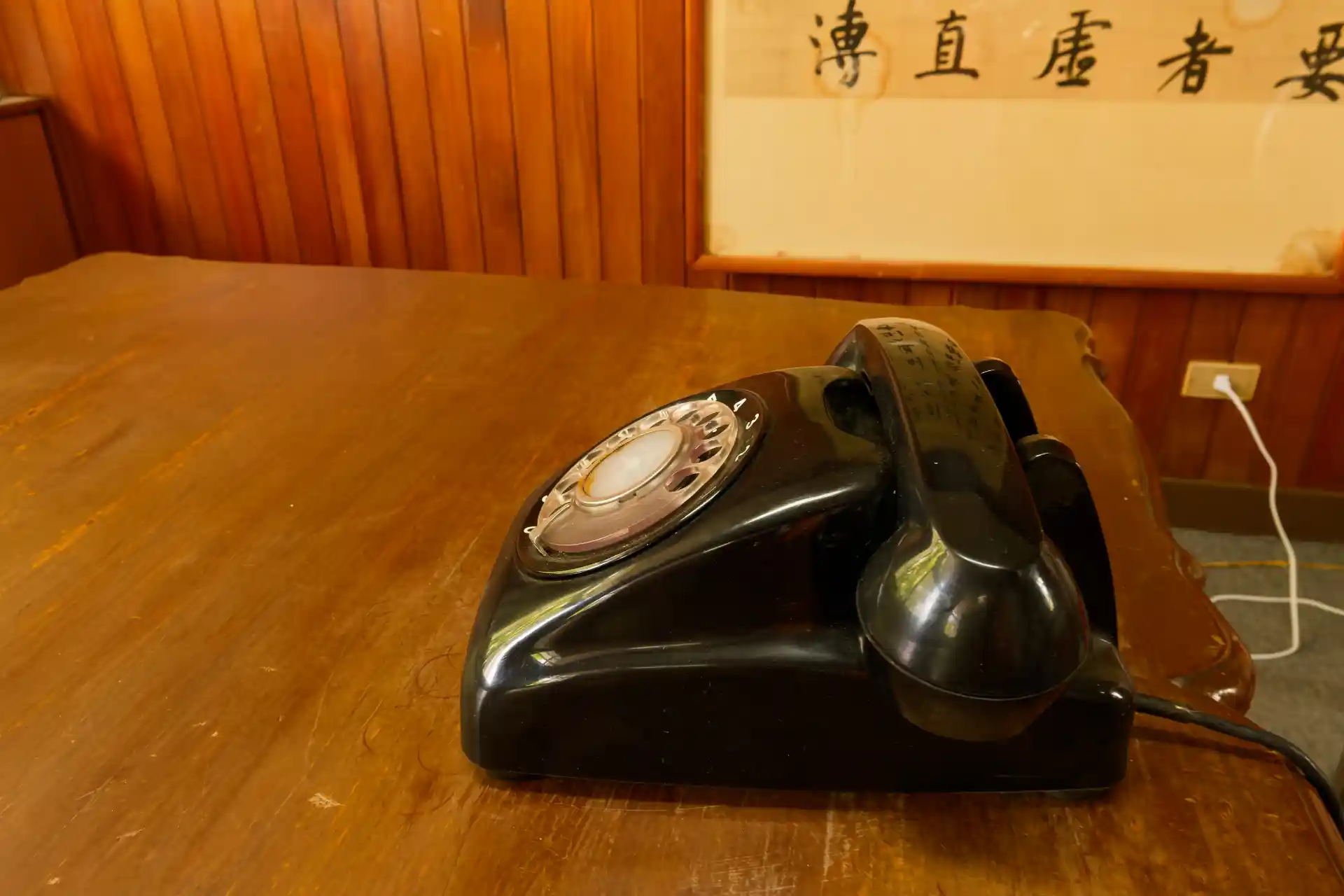 A black rotary dial telephone on a desk.