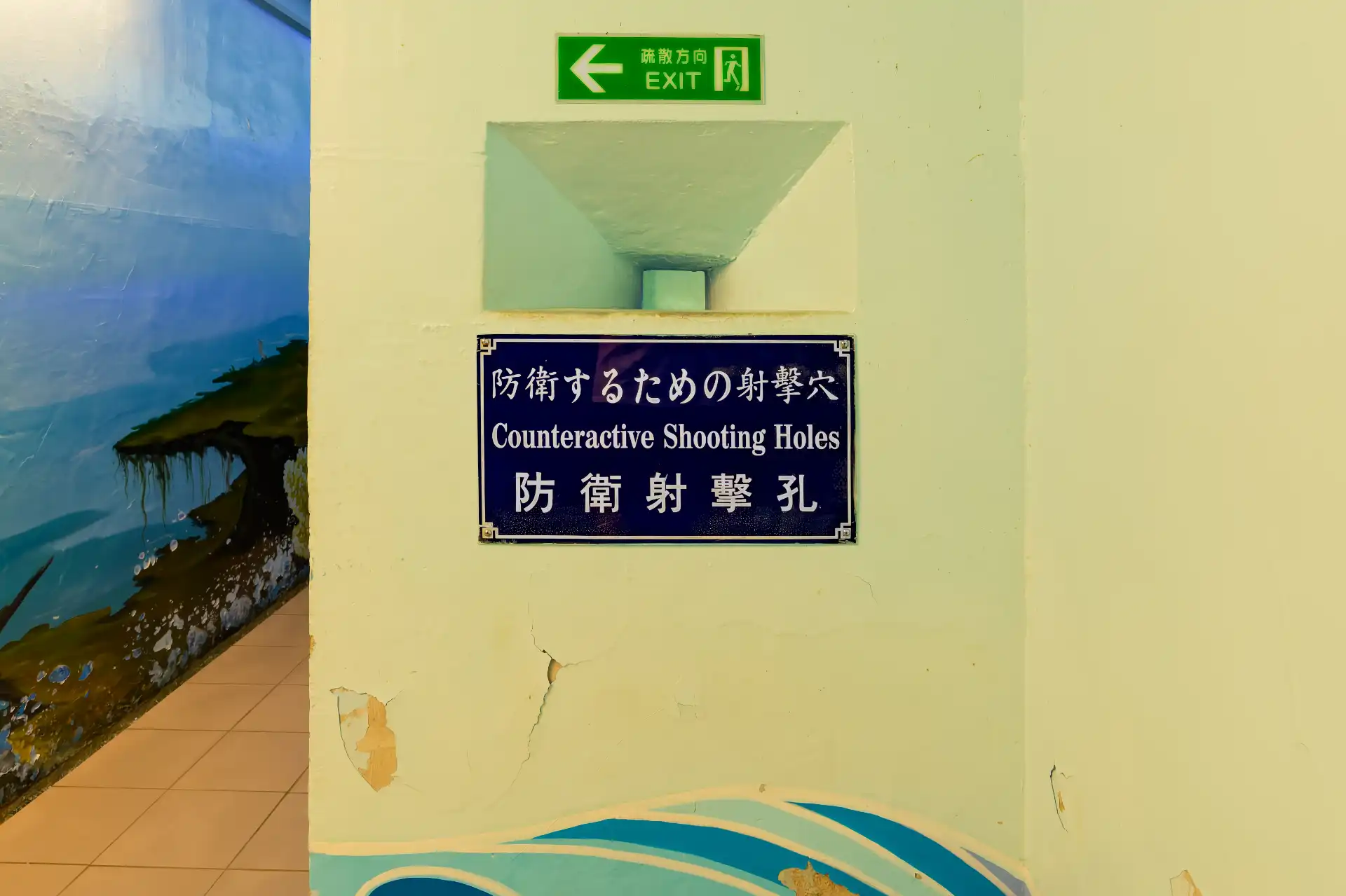 A small square hole in a thick concrete wall in an underground bunker.